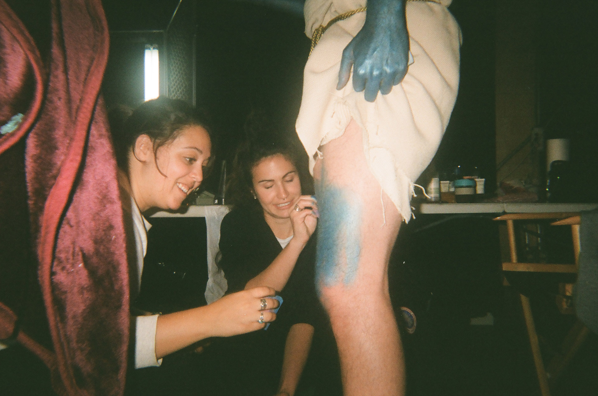 two makeup artists applying blue paint by sponge on legs on actor in behind the scenes for TV series La Loi C'est La Loi filmed by Les Gamins for TV5 Unis