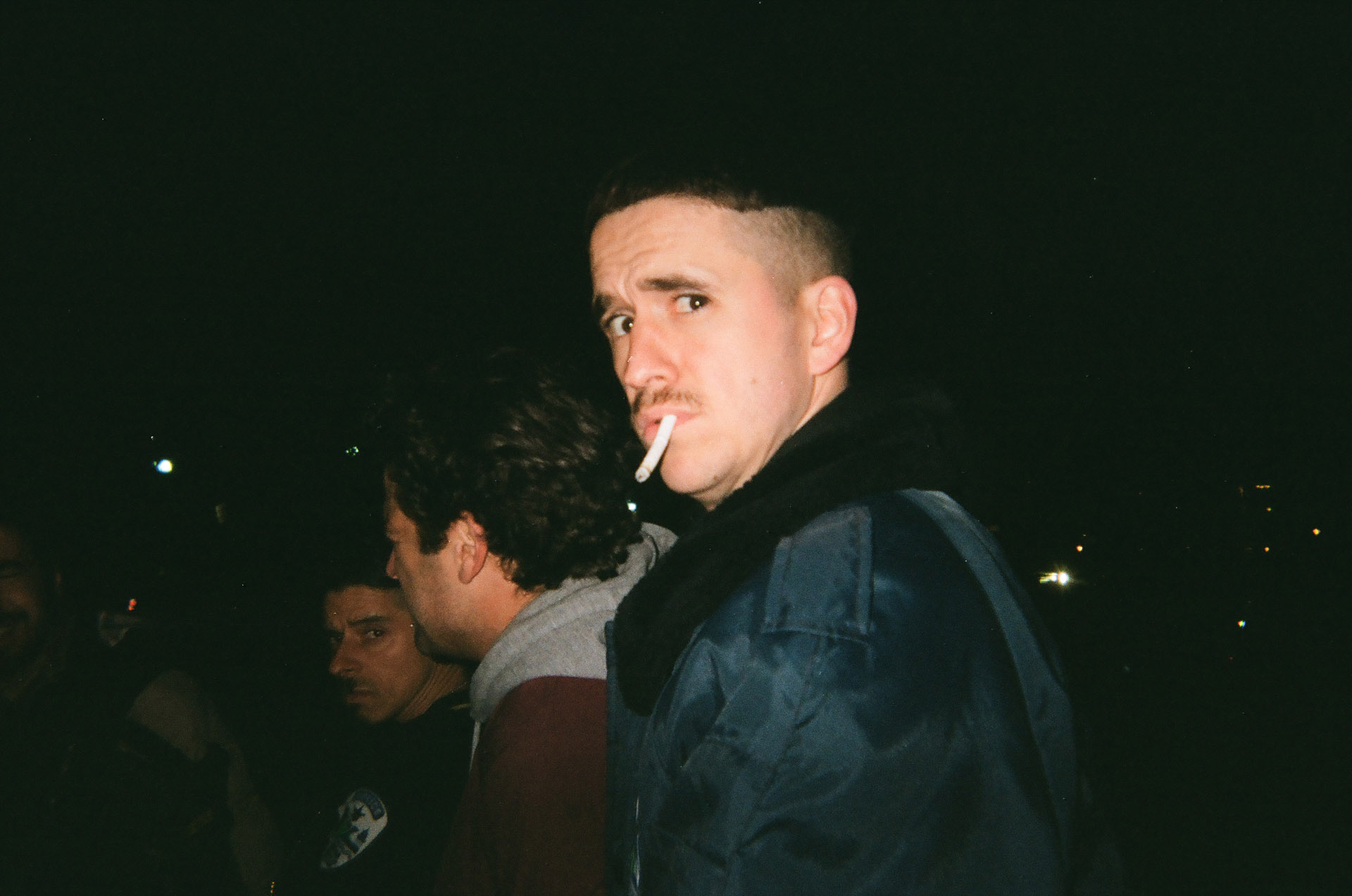 actor Emile Schneider dressed as cop smoking a cigarette looking at camera with eyebrows raised in behind the scenes of TV series La Loi C'est La Loi filmed by Les Gamins for TV5 Unis