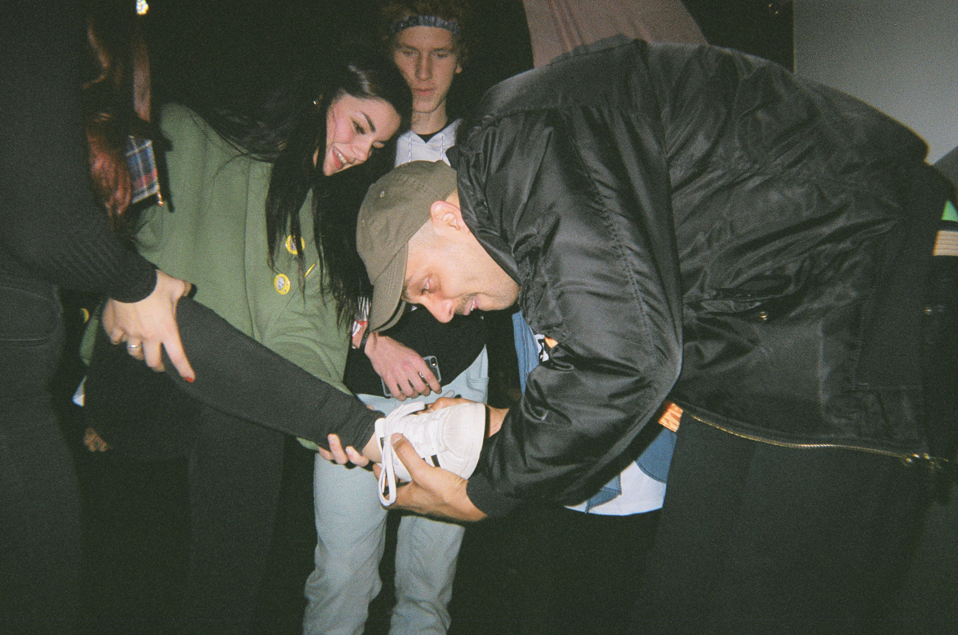Alaclair Ensemble bandmember signing an autograph on a fan's shoe in behind the scenes of L'Osstidfilm documentary filmed by Vincent Ruel-Cote from Les Gamins about L'Osstidtour
