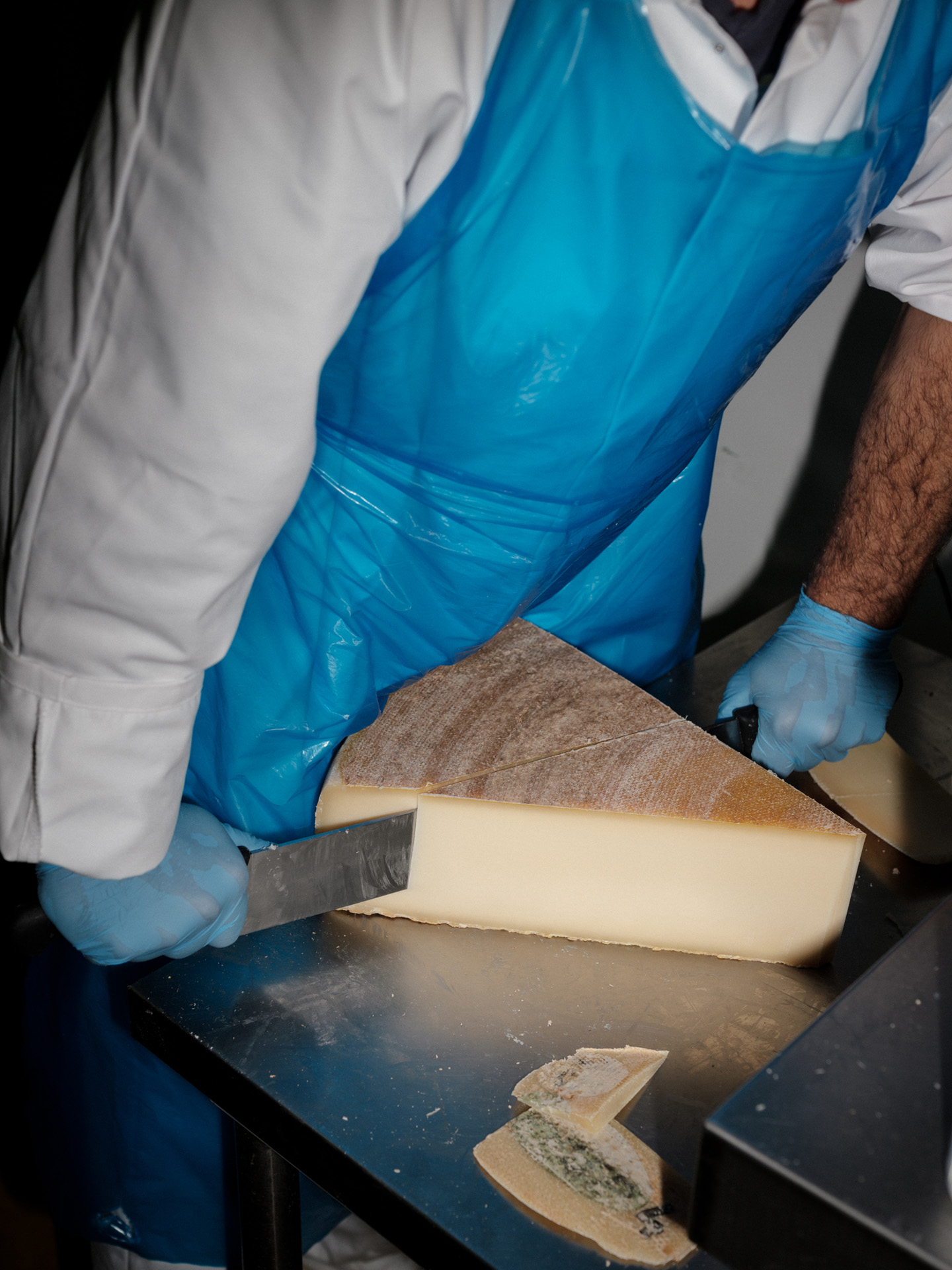worker cutting huge piece of cheese for pasta by Alexi Hobbs in Auvergne for Reflets de France