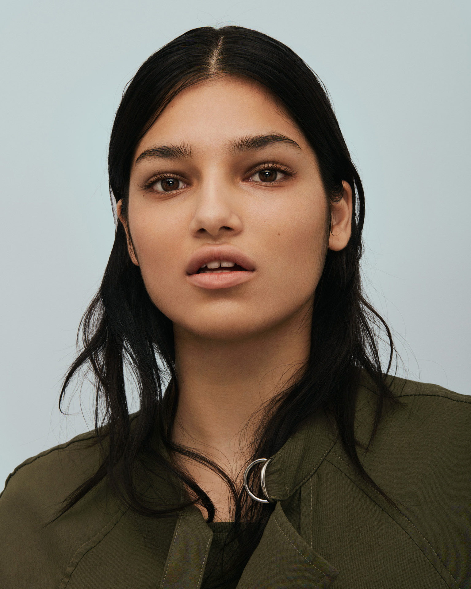 woman in dark green outfit face on light blue background by Maxyme G Delisle for The Ones 2 Watch