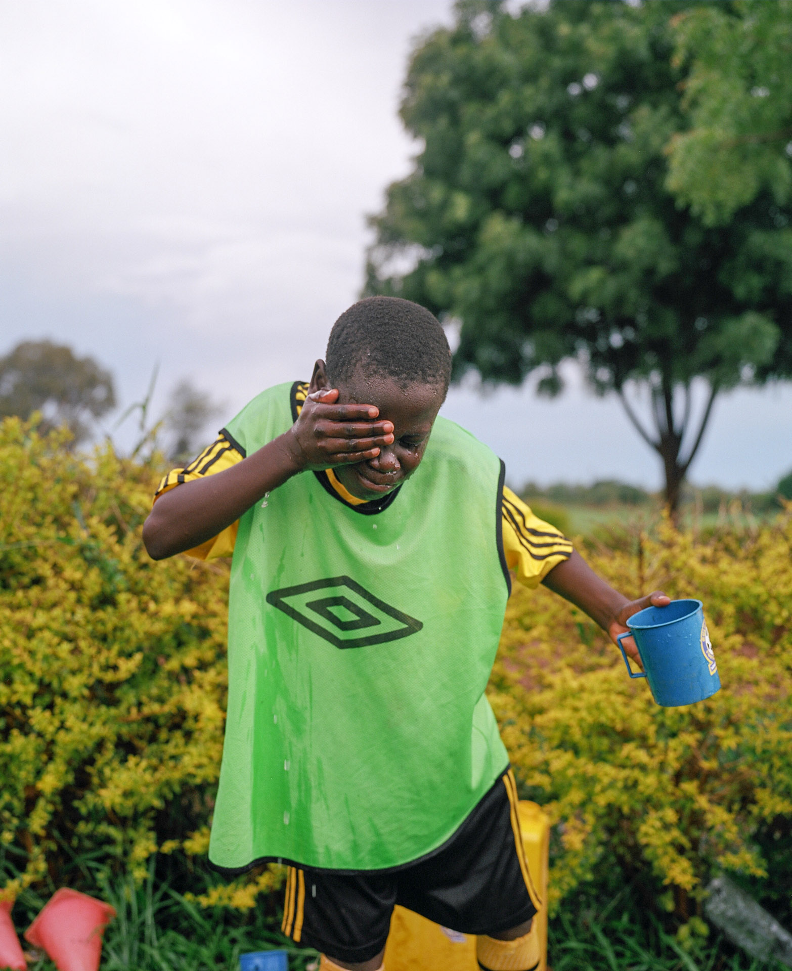 young black boy rinsing his face with water by Alexi Hobbs in Uganda for Football for good with Sportsnet