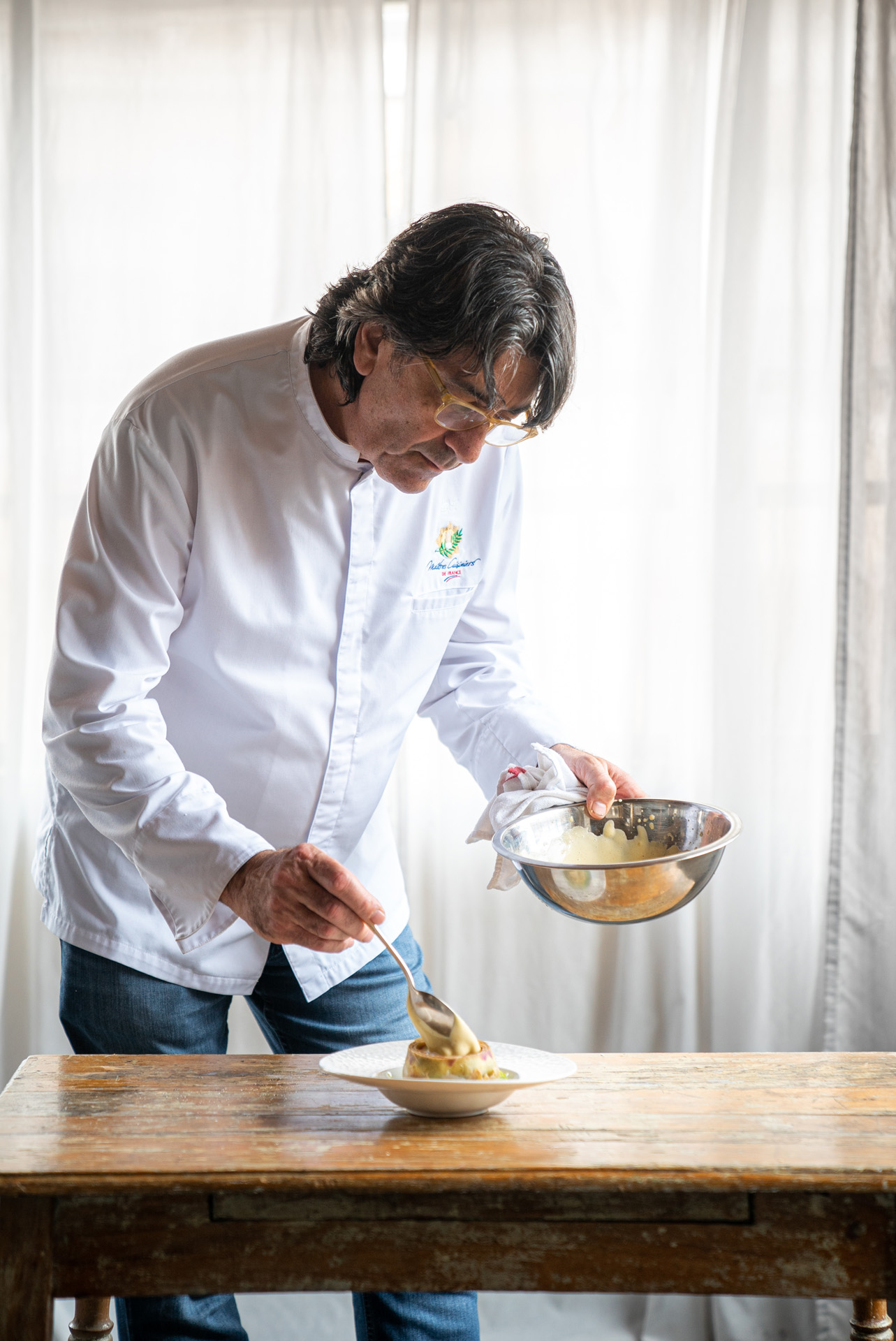 chef Didier Leroy plating his meal on wood table by Bruno Florin for Van Houtte 100th anniversary