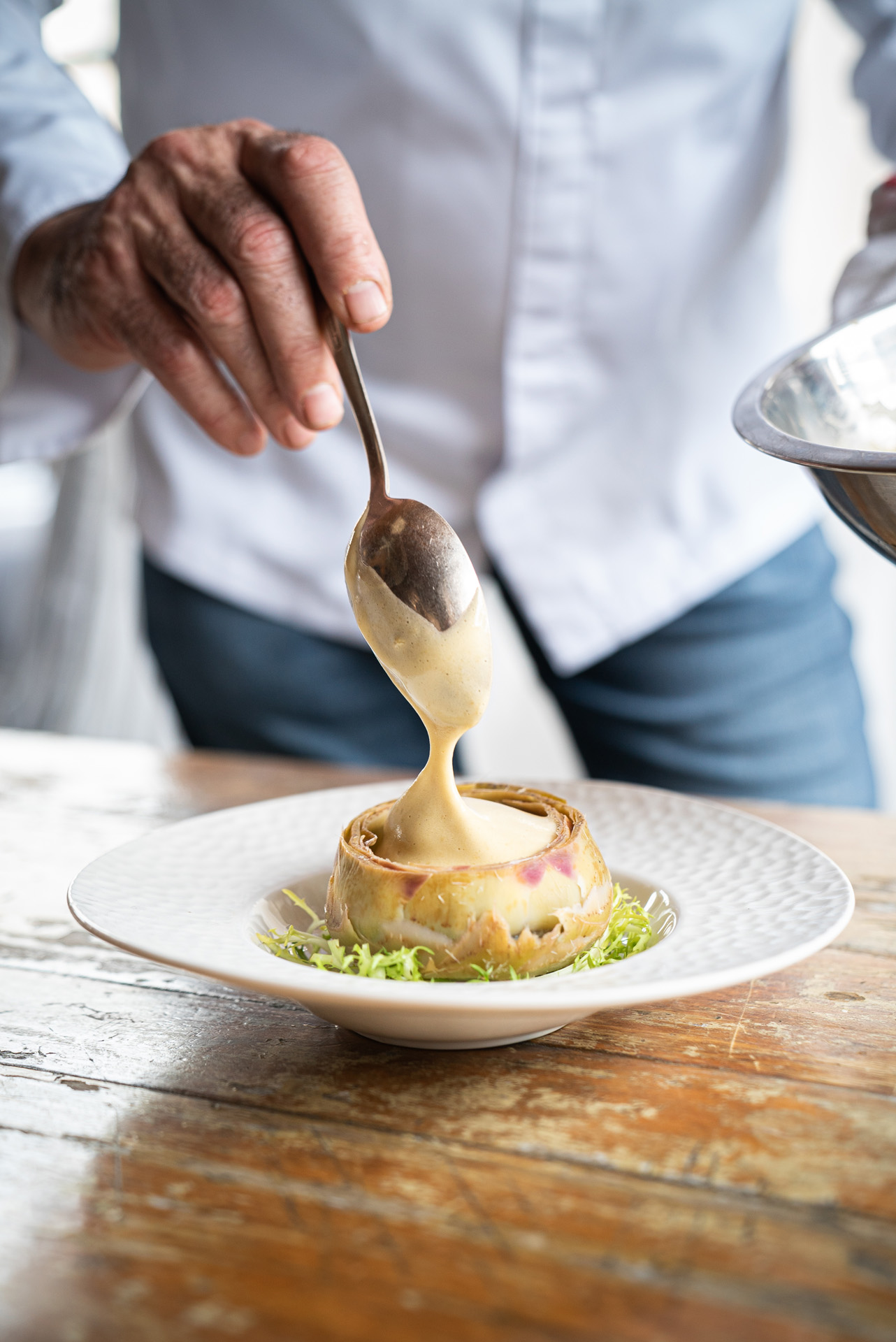 chef Didier Leroy close up of plating his meal on wood table scooping filling with spoon by Bruno Florin for Van Houtte 100th anniversary