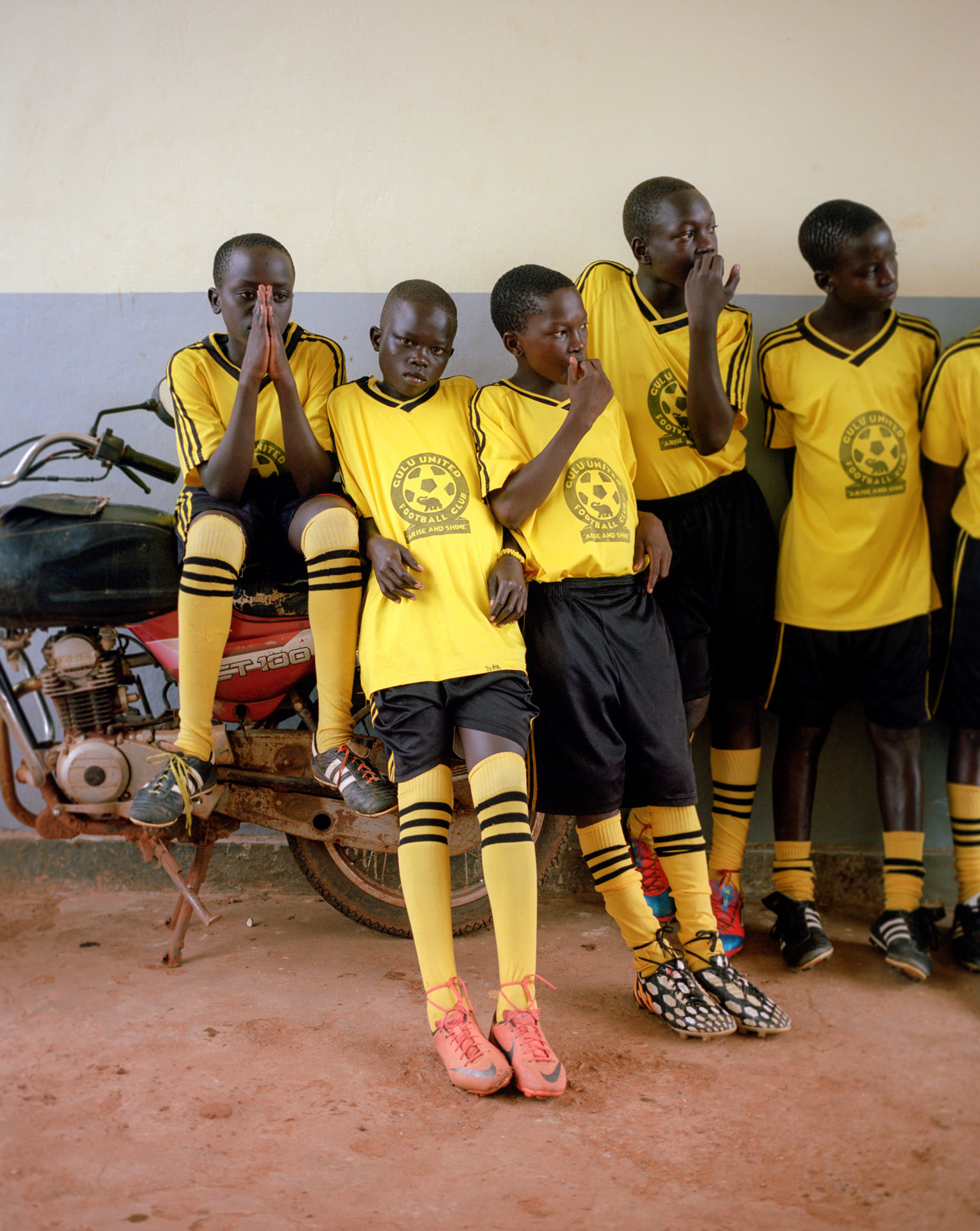 young black boys soccer players waiting on parked scooter by Alexi Hobbs in Uganda for Football for good with Sportsnet
