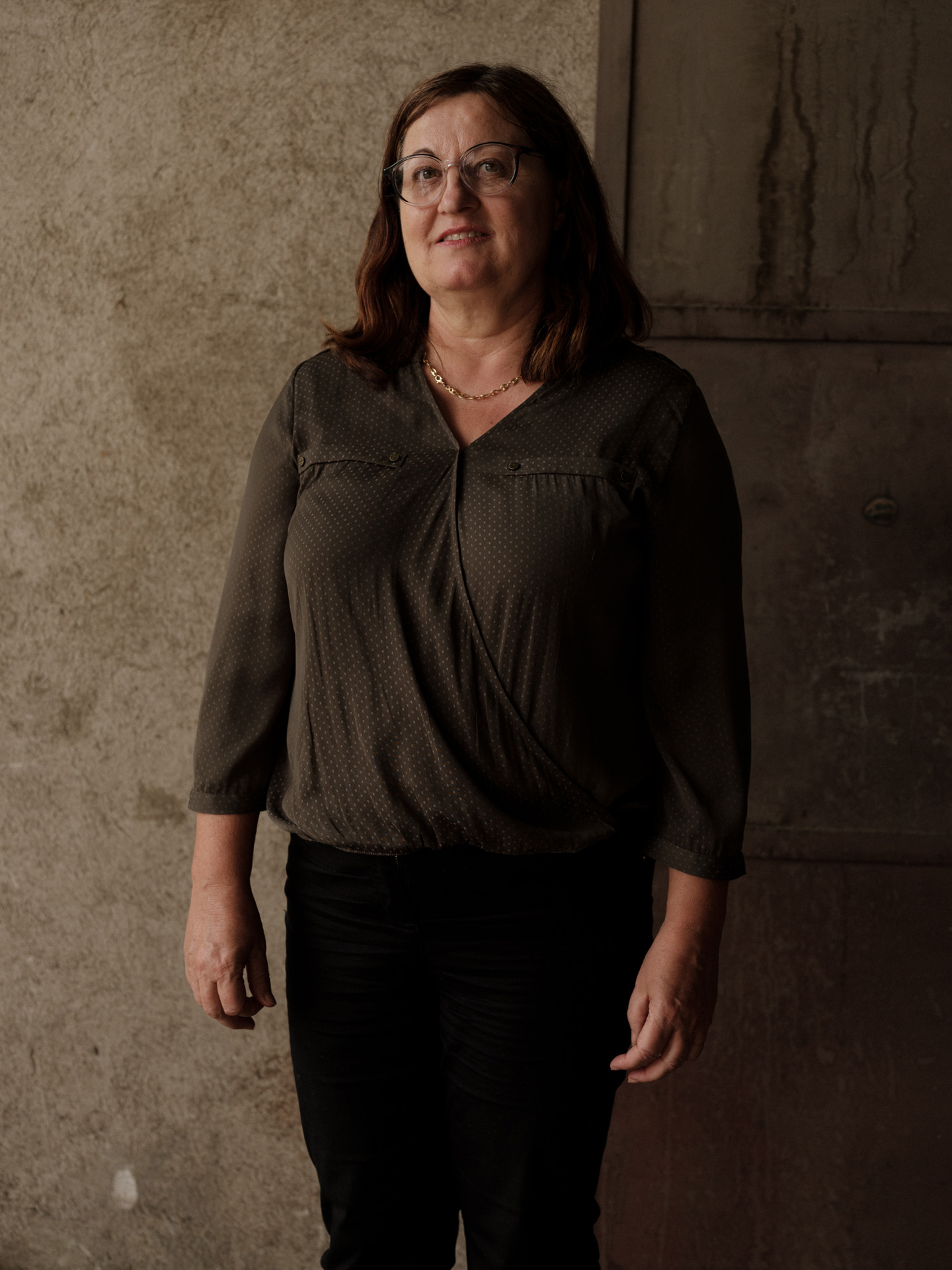 portrait of lady in front of concrete wall dressed in brown by Alexi Hobbs in Auvergne for Reflets de France