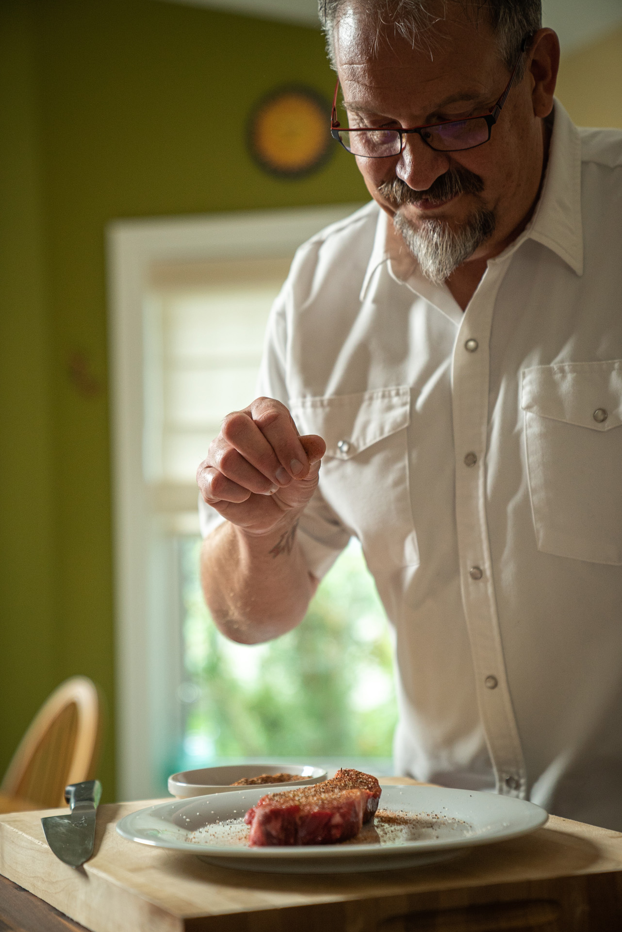 chef Michael Allemeier sprinkling spices over pieces of red meat by Bruno Florin for Van Houtte 100th anniversary