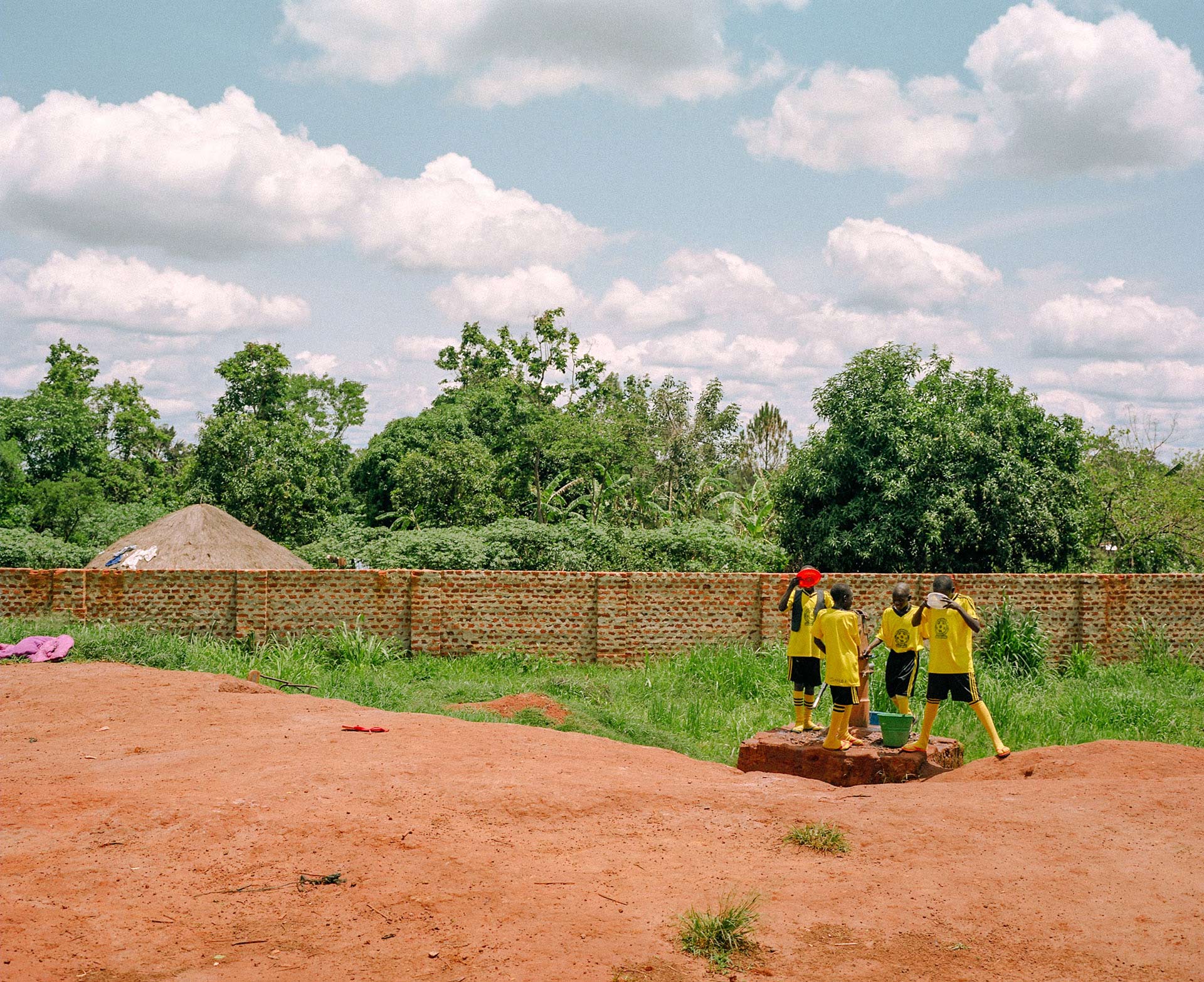 young soccer players drinking water from buckets by Alexi Hobbs in Uganda for Football for good with Sportsnet