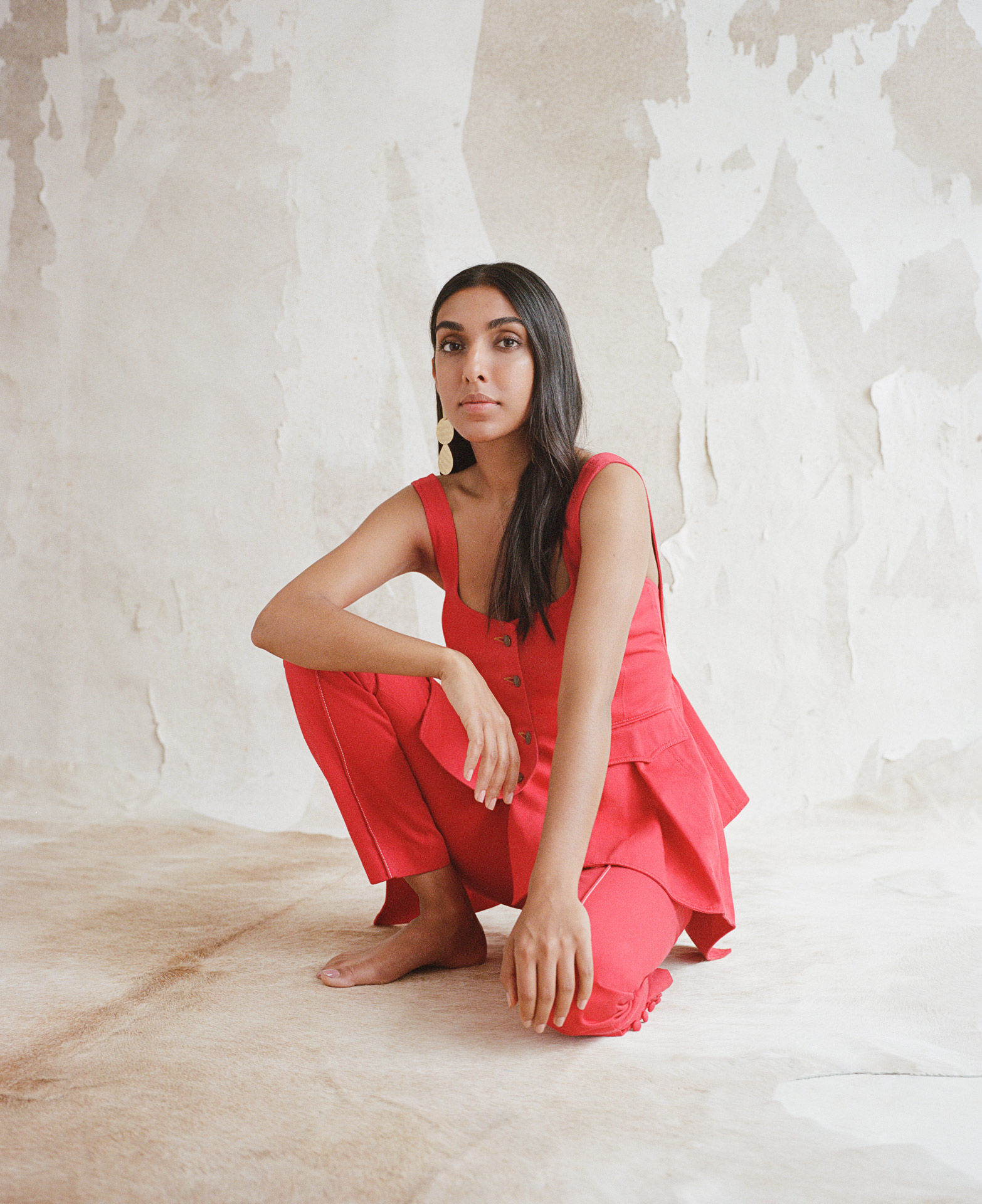 writer Rupi Kaur wearing red ensemble looking at camera by Oumayma B Tanfous for Vogue Espana