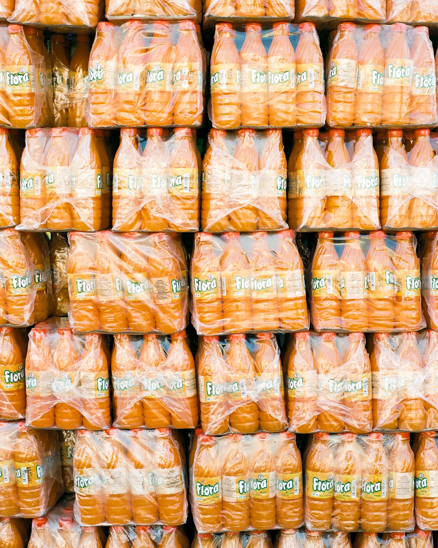 stack of orange bottled drinks named Flora by Alexi Hobbs in Uganda for Football for Good with Sportsnet