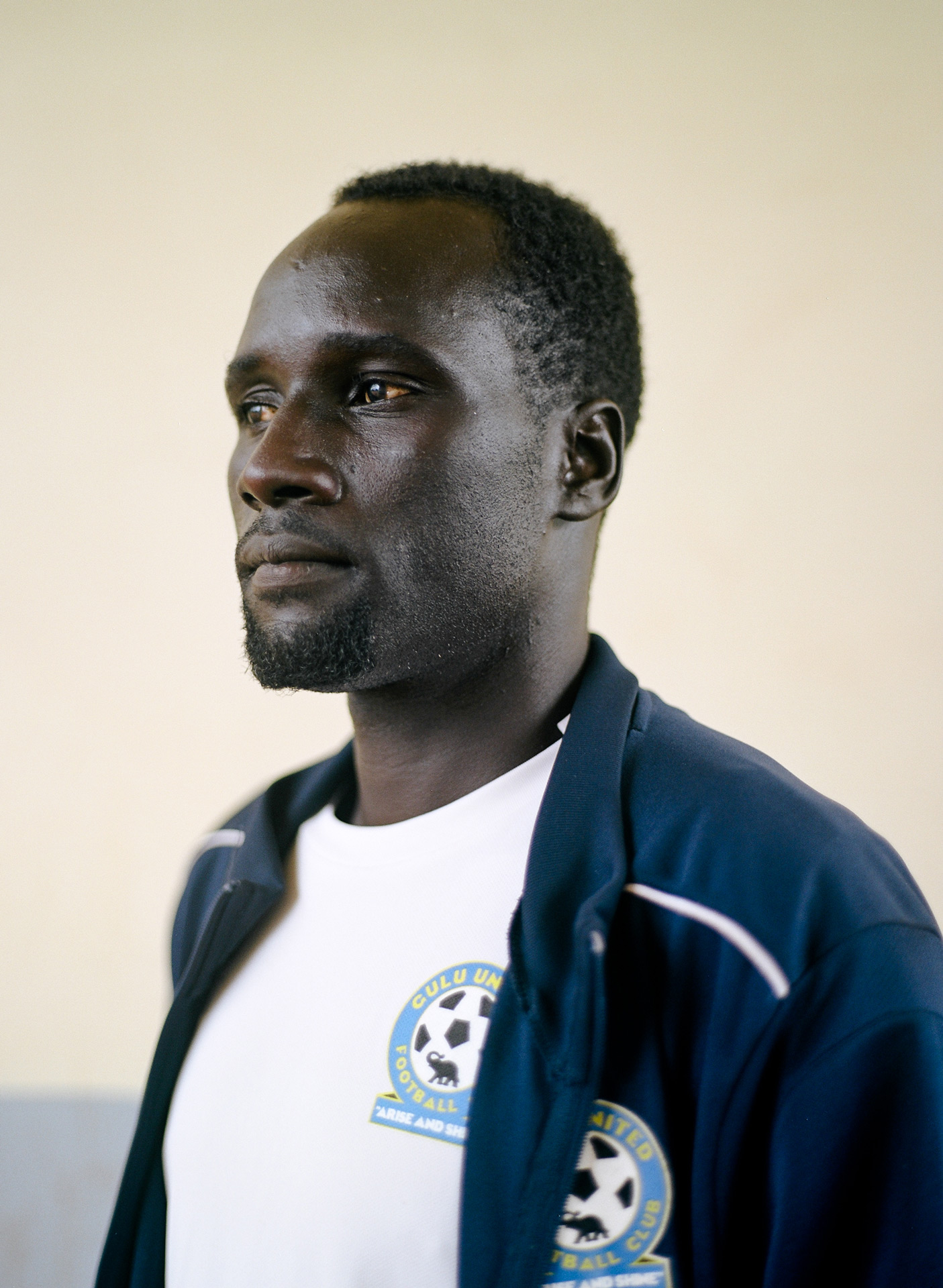 portrait of black man looking away dressed as coach of team by Alexi Hobbs in Uganda for Football for Good with Sportsnet
