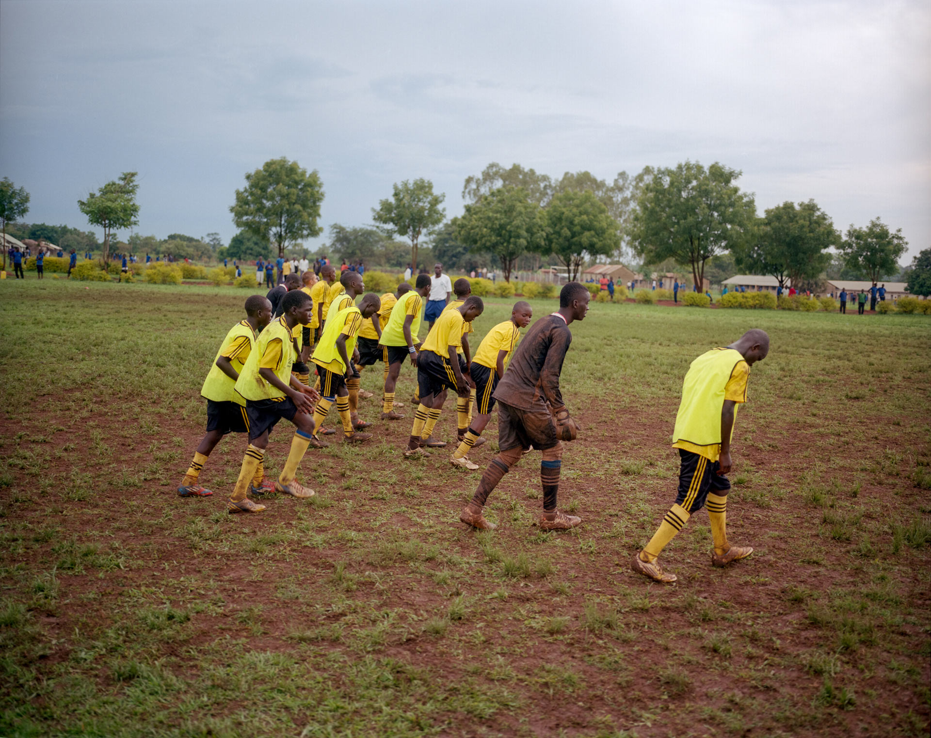 group of young black boys running in line and warming up for match wearing yellow soccer jersey by Alexi Hobbs in Uganda for Football for Good with Sportsnet