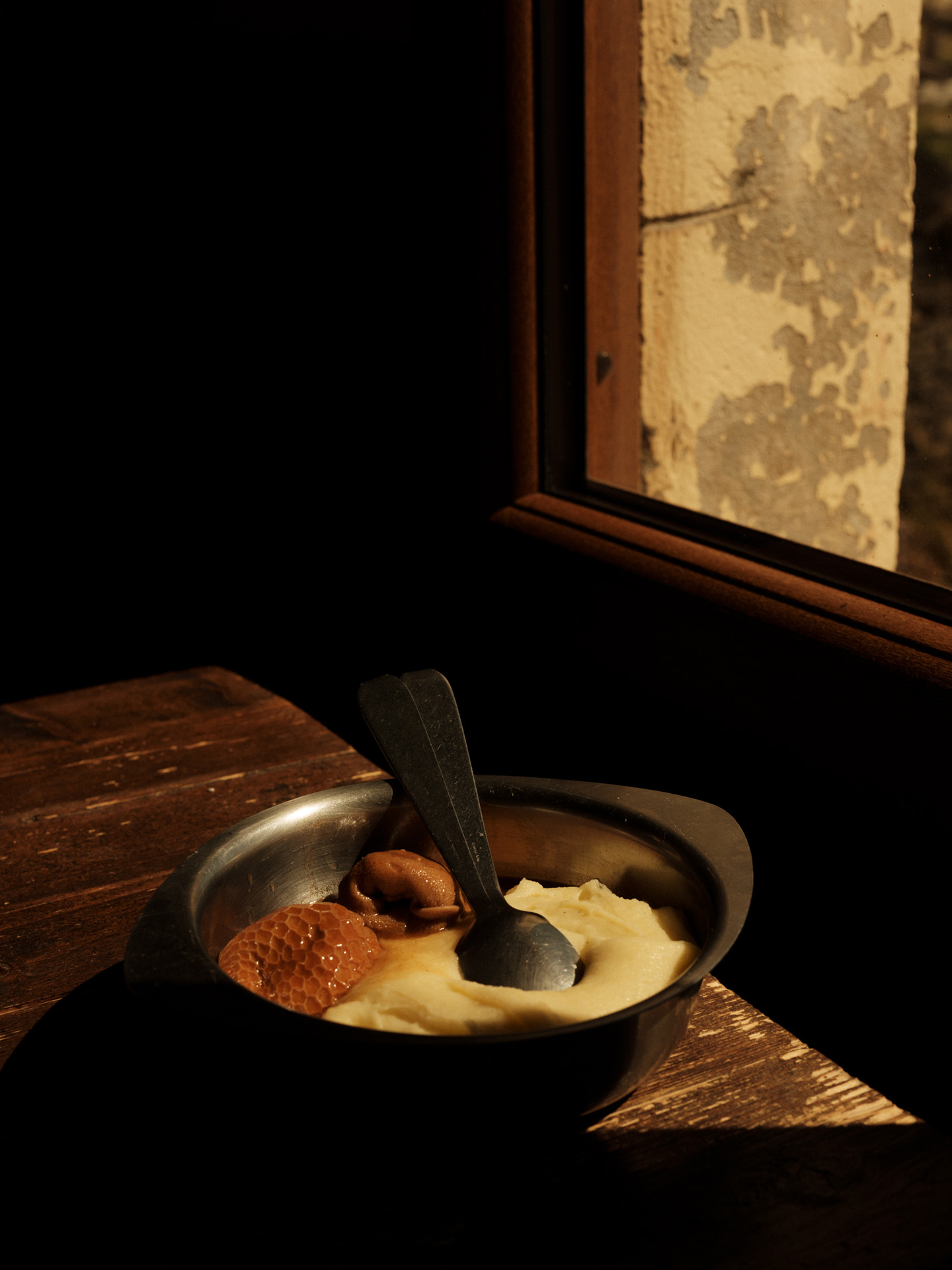 metal plate of food composed of mashed potatoes and unidentified other things on wood table by Alexi Hobbs in Auvergne for Reflets de France