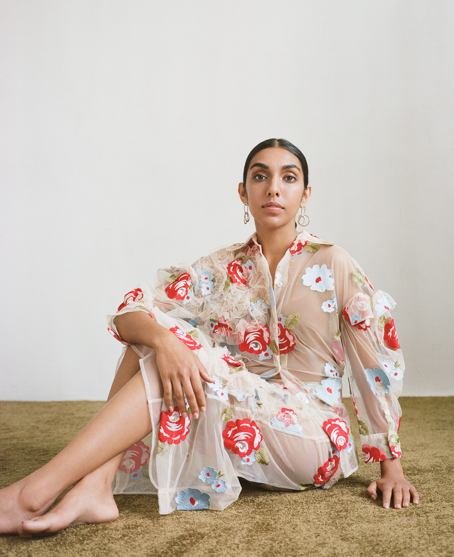 writer Rupi Kaur wearing flower dress looking at camera by Oumayma B Tanfous for Vogue Espana