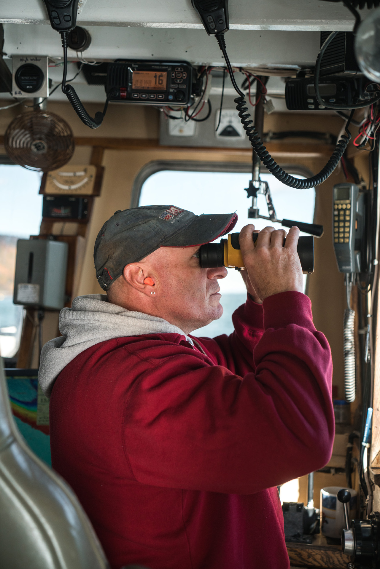 boat captain wearing red jacket looking through binoculars by Bruno Florin for Ricardo Magazine in Bay of Fundy
