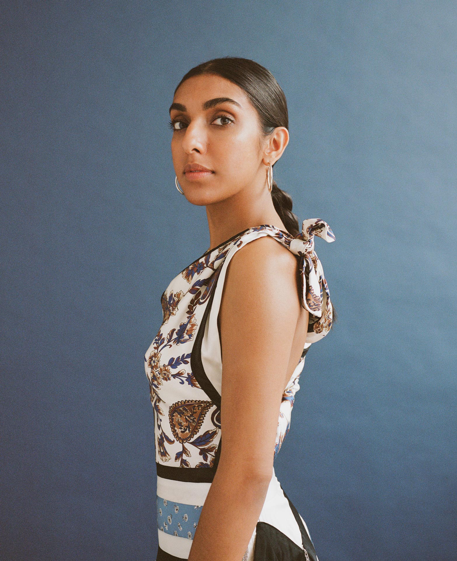 writer Rupi Kaur on blue background looking at camera by Oumayma B Tanfous for Vogue Espana
