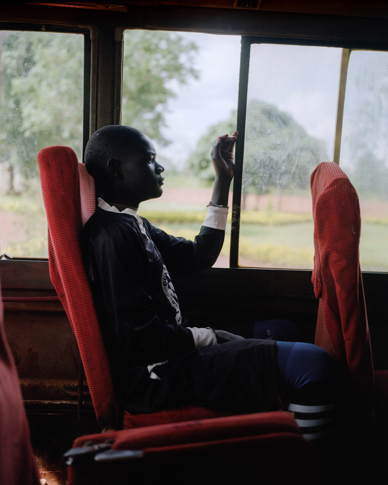 young black boy in bus looking outside by Alexi Hobbs in Uganda for Football for good with Sportsnet