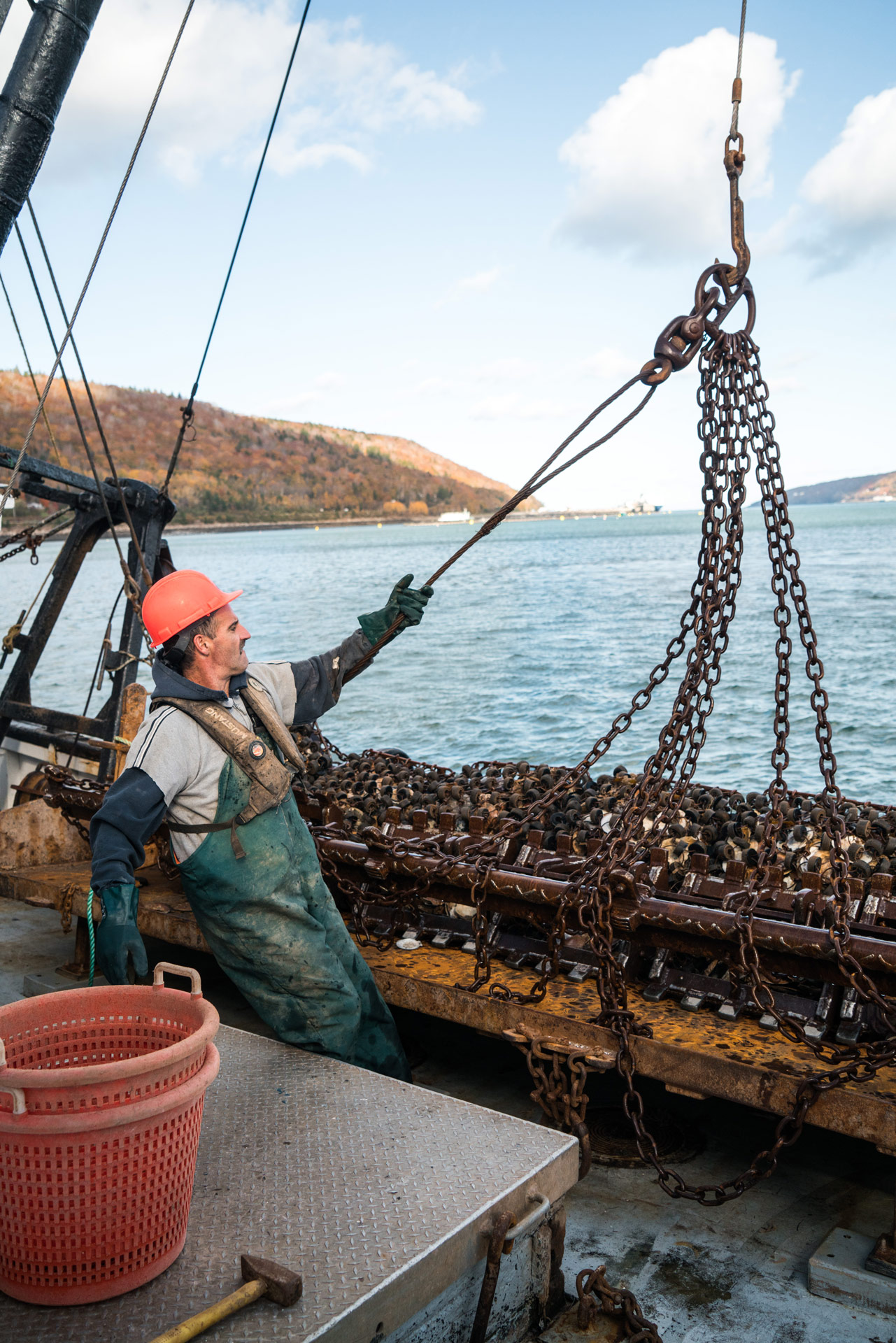 fisherman wearing red helmet stirring the fishing platform by Bruno Florin for Ricardo Magazine in Bay of Fundy