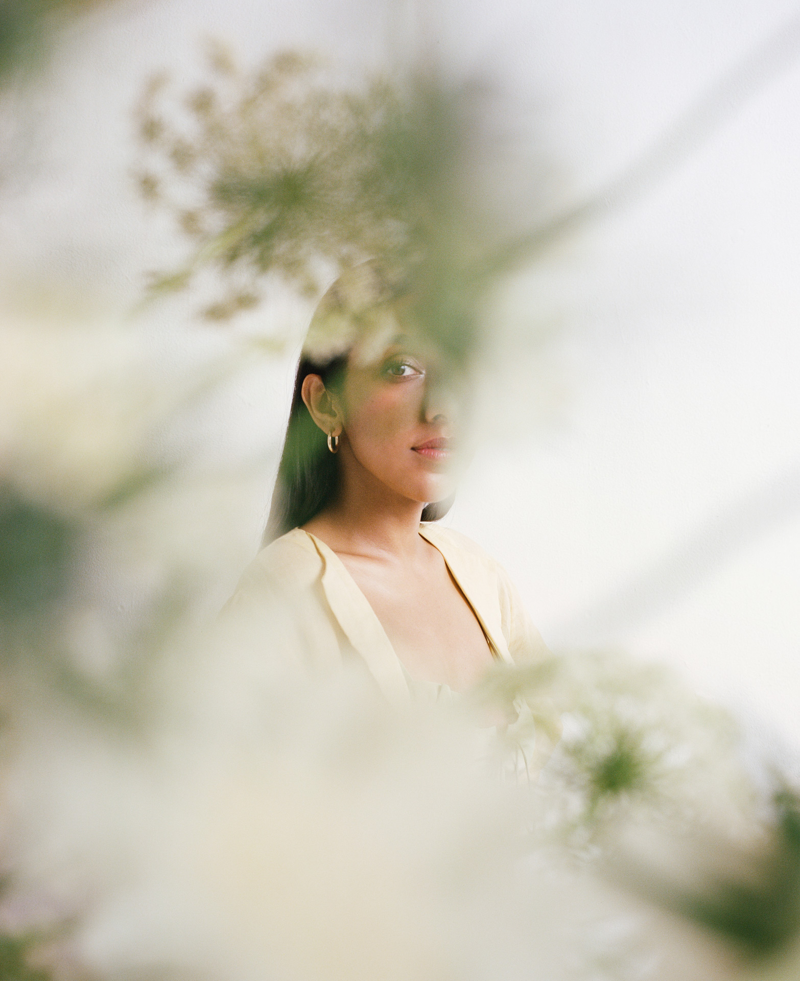 writer Rupi Kaur eyes open behind plants by Oumayma B Tanfous for Vogue Espana