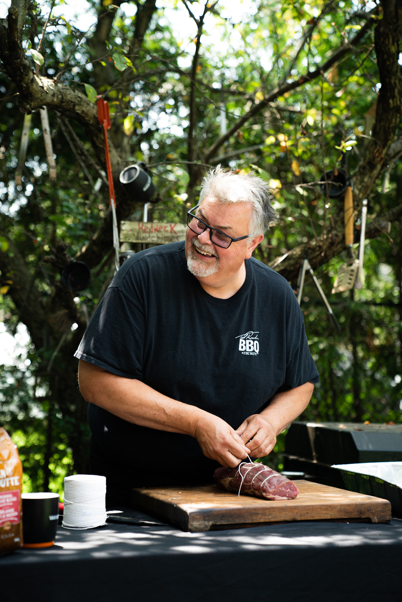 chef Ted Reader tying up a piece of meat with rope cooking outside by Bruno Florin for Van Houtte 100th anniversary