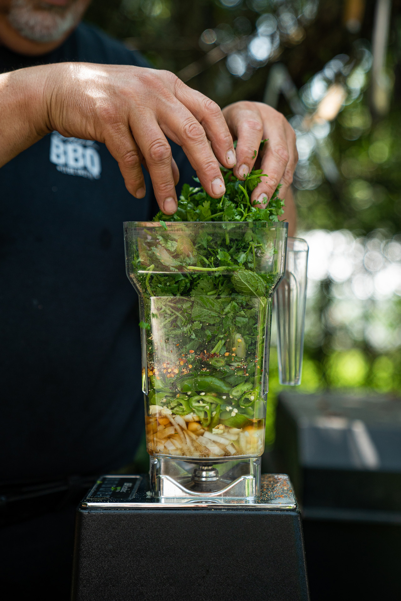 chef Ted Reader filling up a blender with fresh herbs garlic and stuff cooking outside by Bruno Florin for Van Houtte 100th anniversary