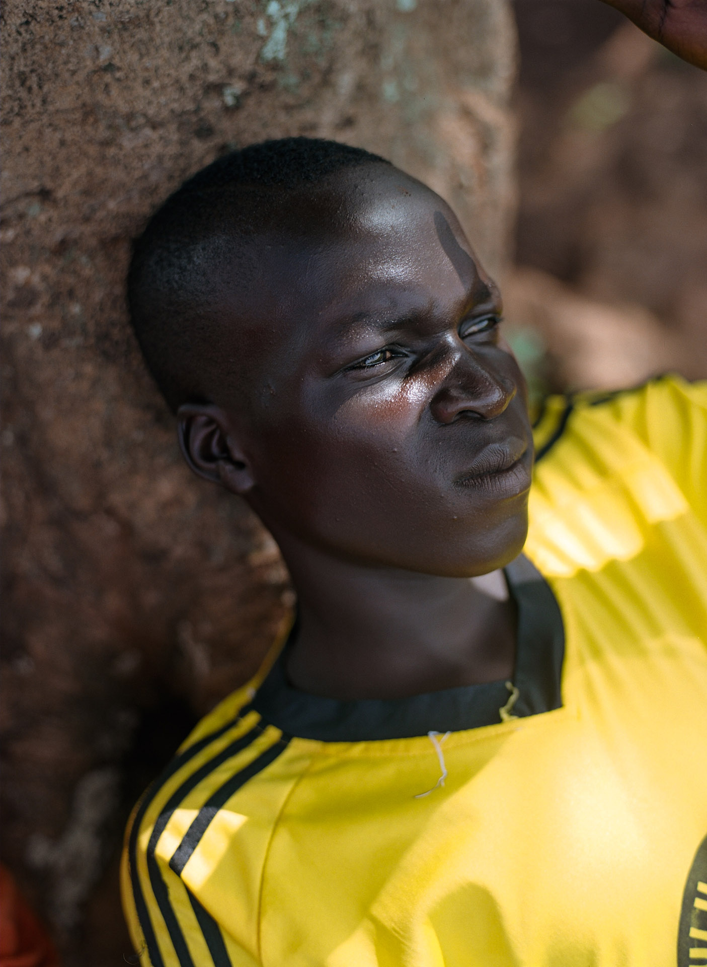 young black boy resting in the shade against a tree by Alexi Hobbs in Uganda for Football for good with Sportsnet