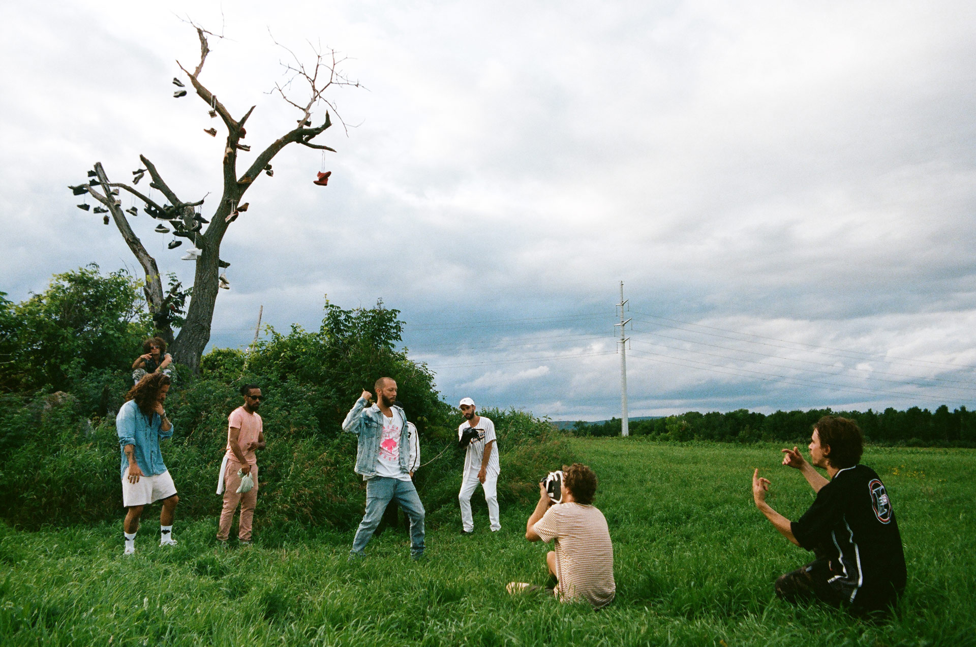 Vincent Ruel-Cote from Les Gamins crouching in field while filming Alaclair Ensemble hip hop collective music video Felix featuring rapper Souldia