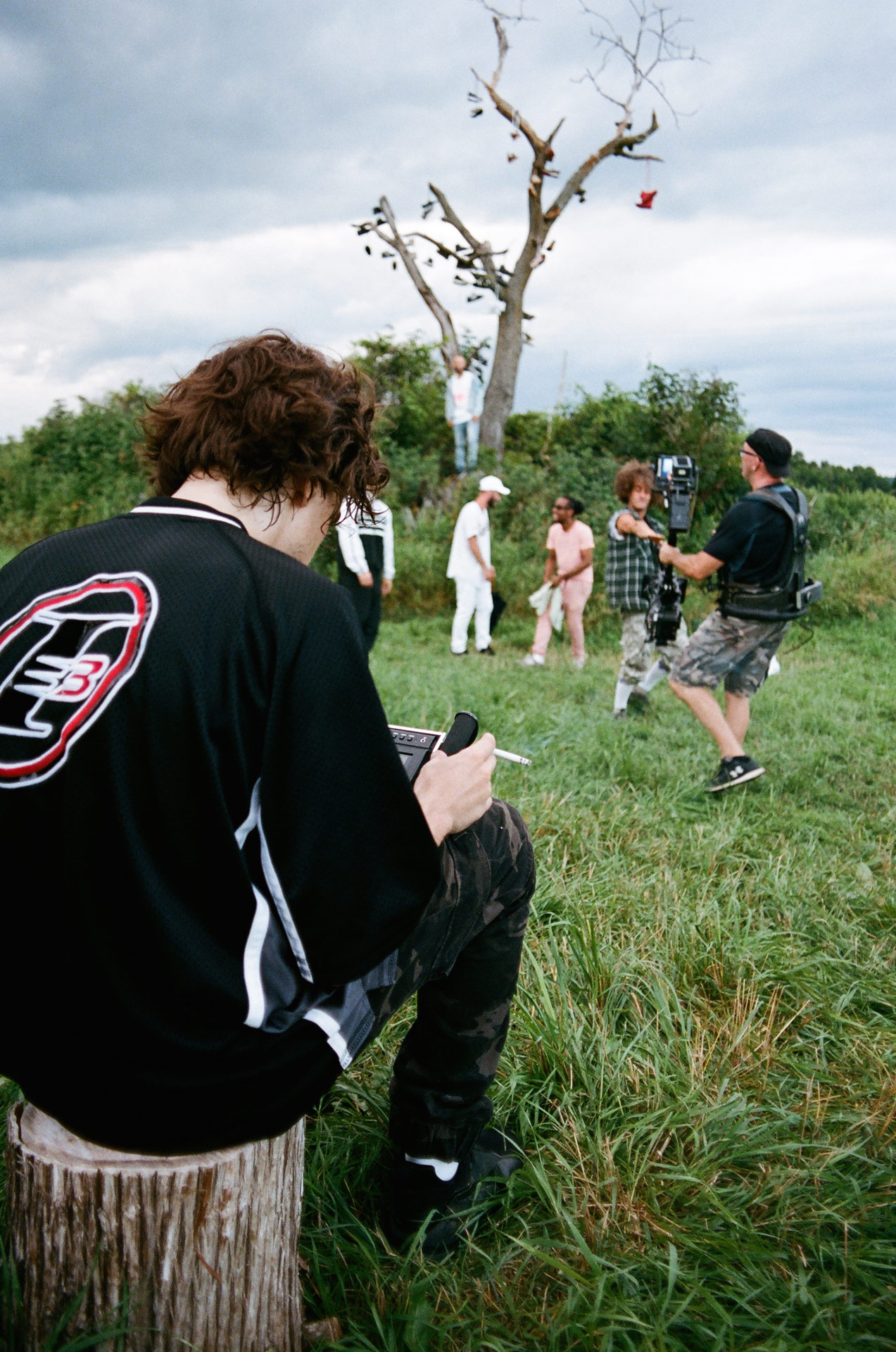 Vincent Ruel-Cote from Les Gamins sitting on wood log checking footage while filming Alaclair Ensemble hip hop collective music video Felix featuring rapper Souldia