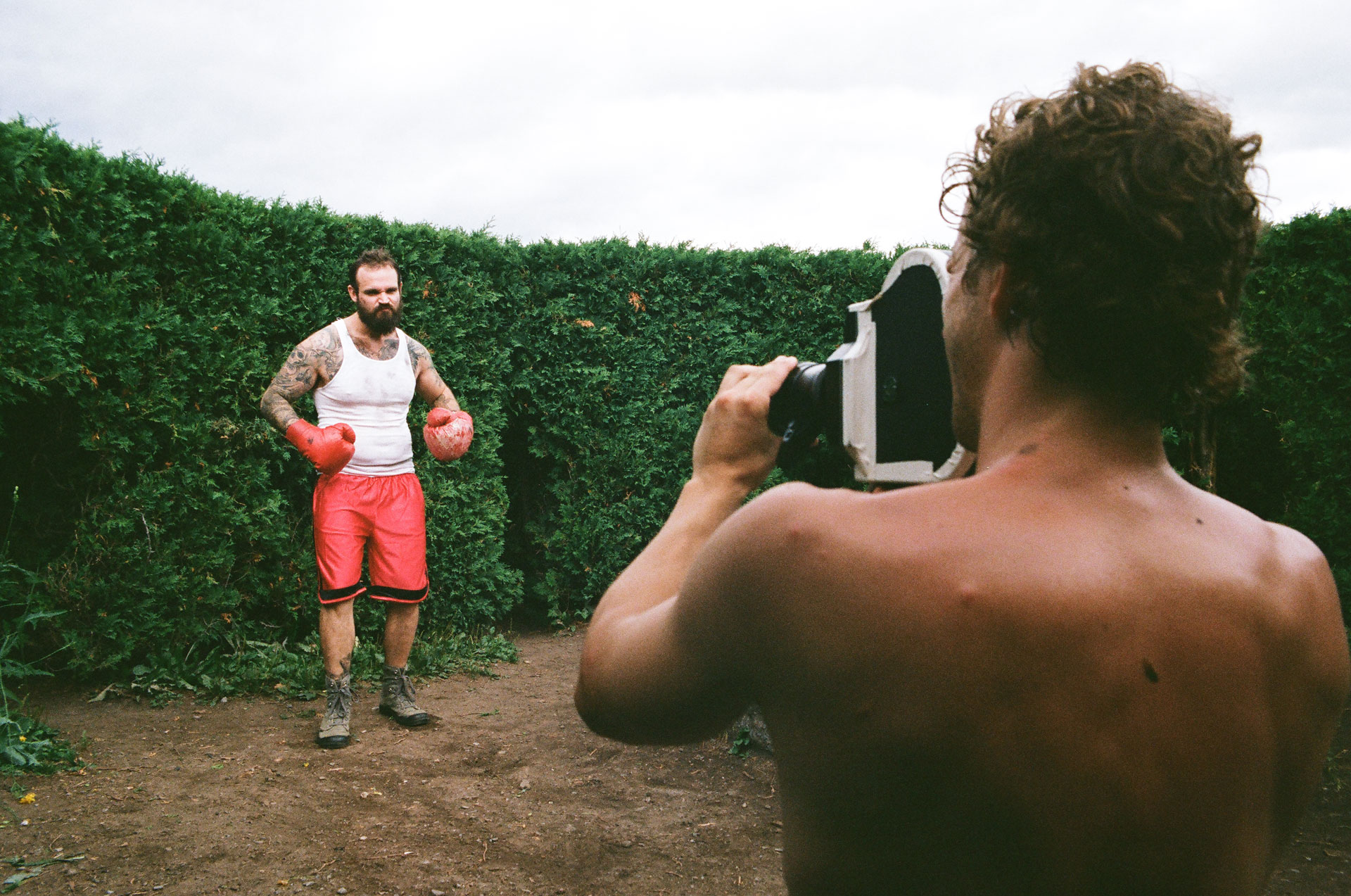 actor dressed as boxer with red gloves being filmed by a shirtless cameraman for Alaclair Ensemble hip hop collective music video Felix filmed by Les Gamins featuring rapper Souldia
