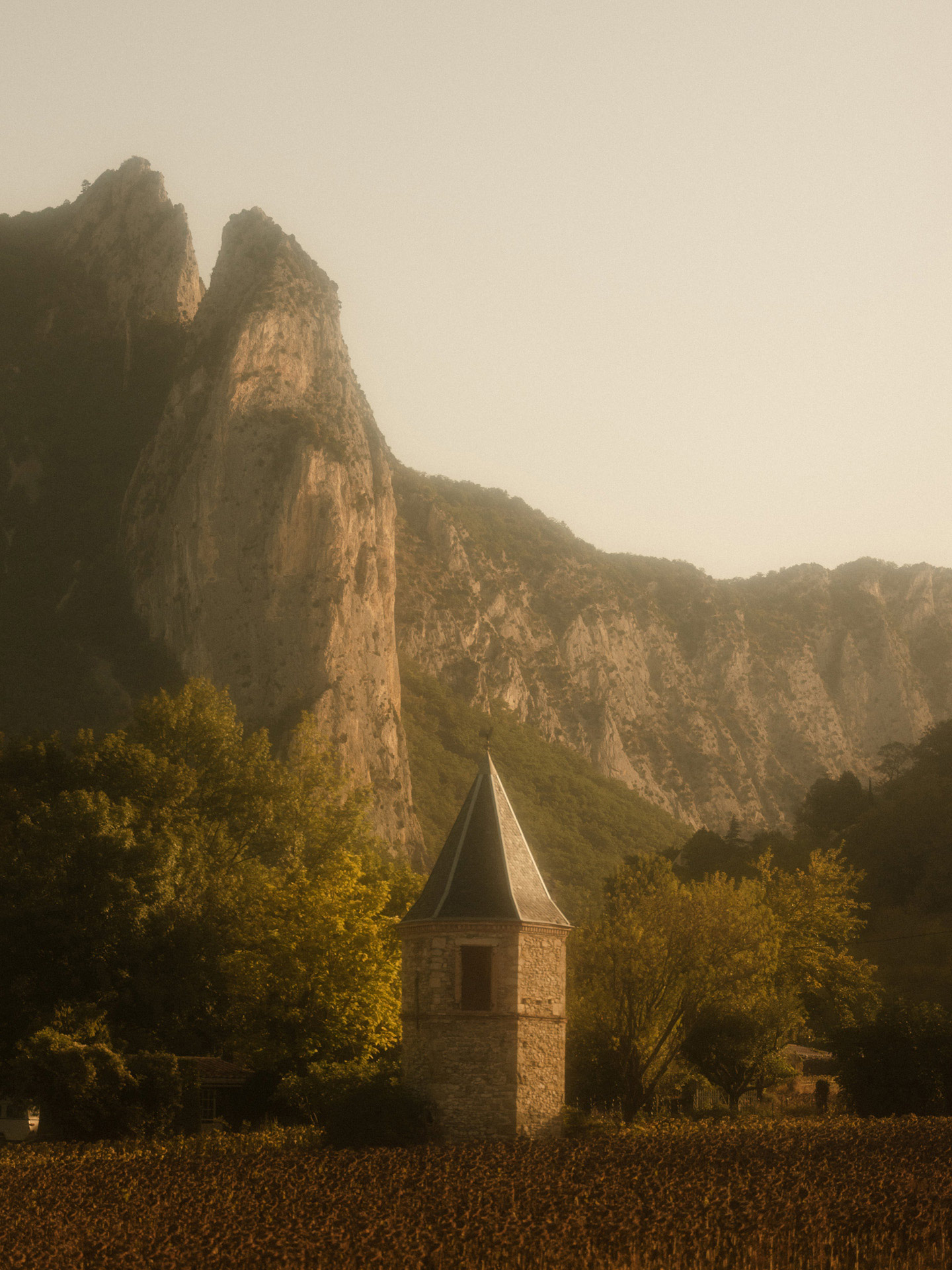 medieval looking tower made of stone in middle of field by Alexi Hobbs in Auvergne for Reflets de France