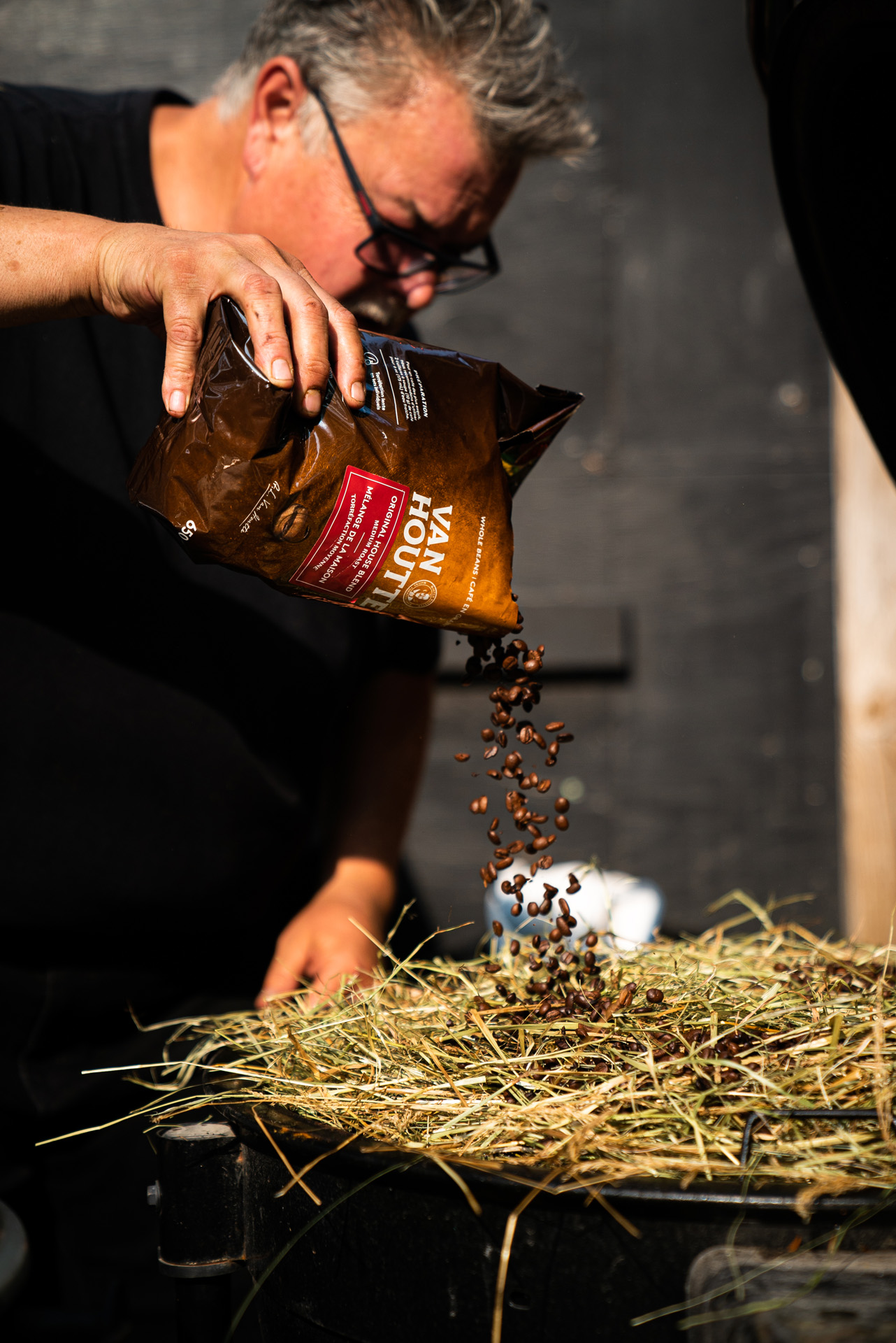 chef Ted Reader pouring roasted coffee beans on cooking hay by Bruno Florin for Van Houtte 100th anniversary