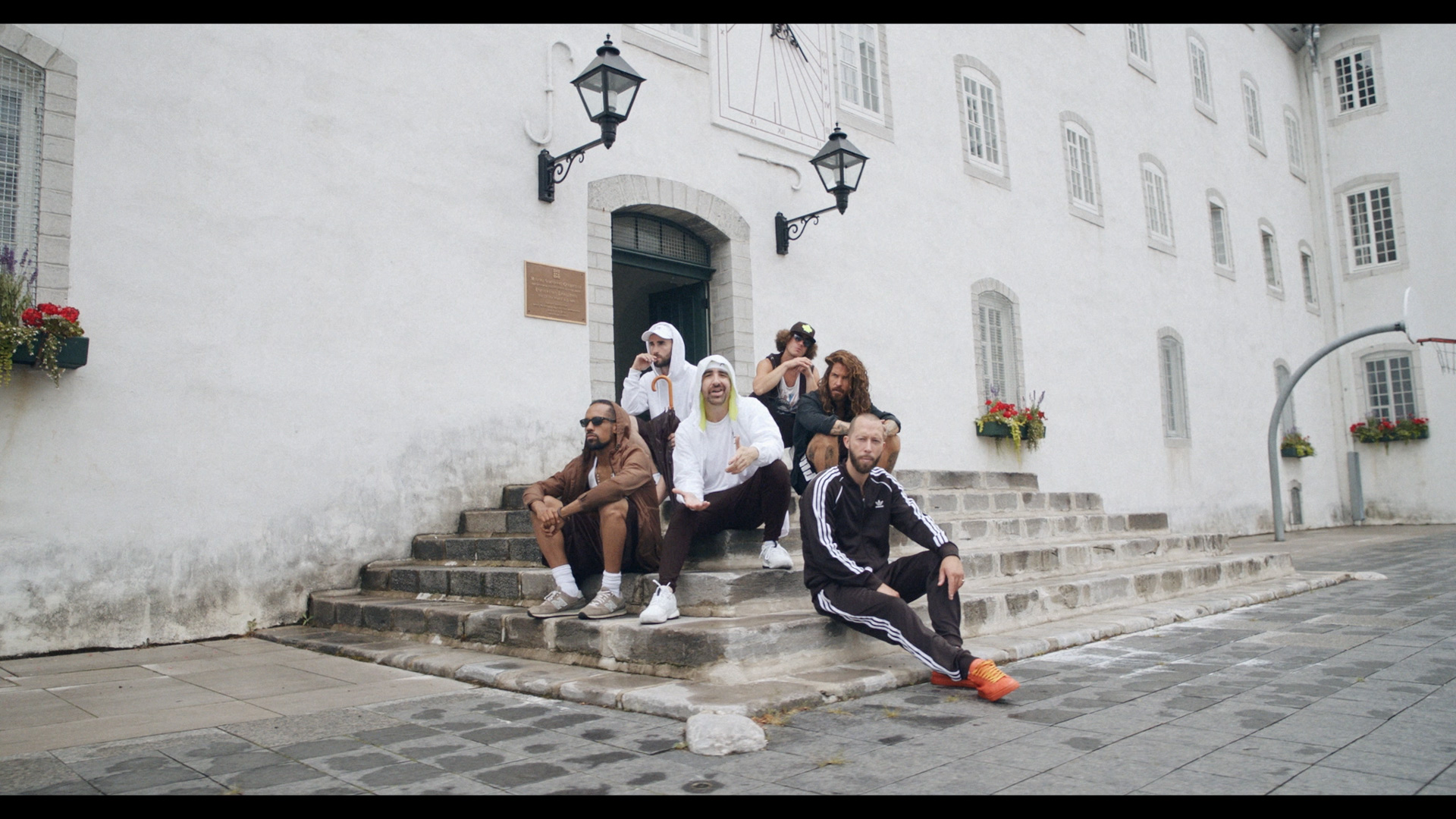Alaclair Ensemble hip hop collective members sitting in stone stairs of building looking at camera for music video Felix filmed by Les Gamins featuring rapper Souldia