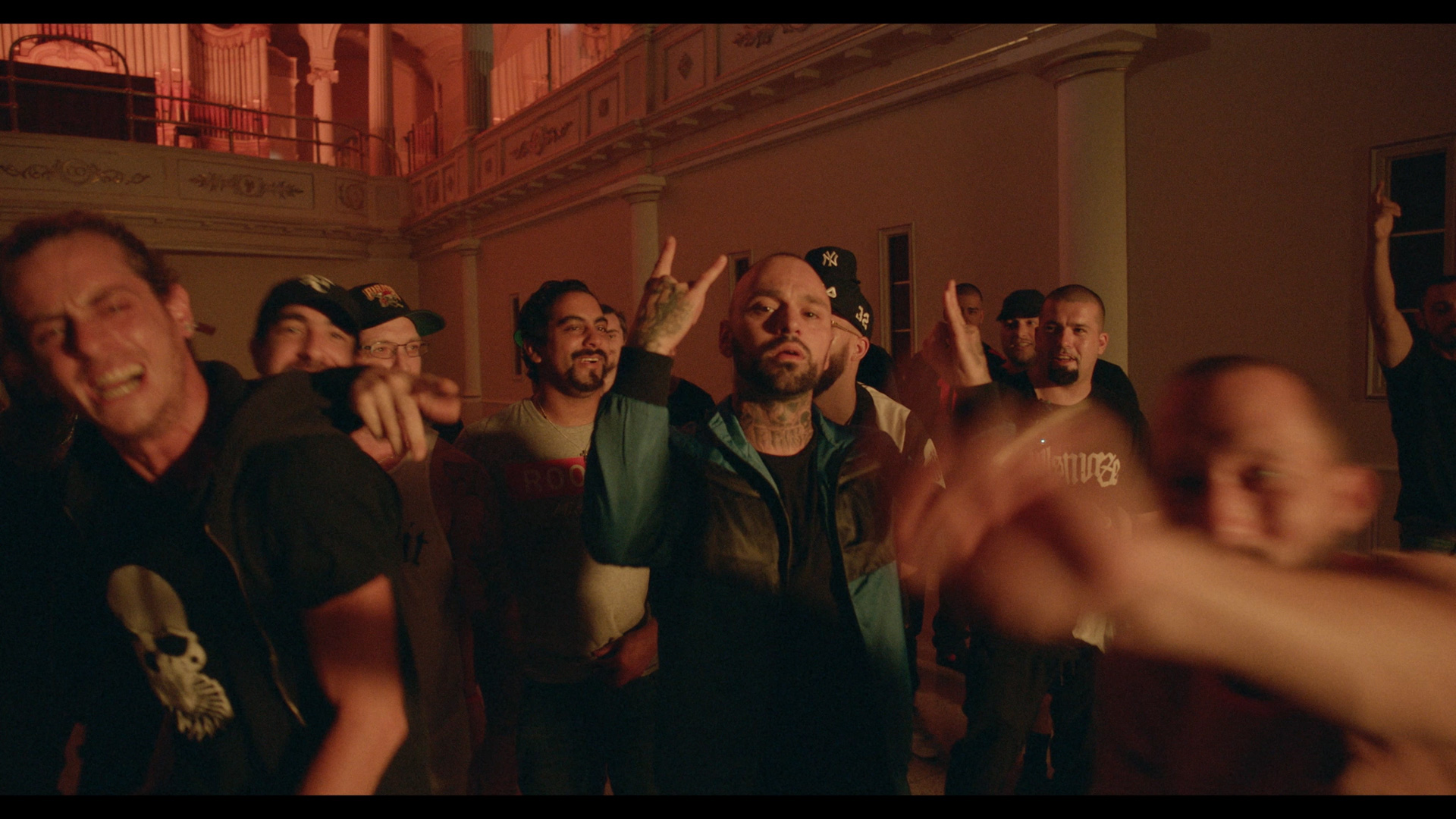 Alaclair Ensemble hip hop collective members dancing in building bathed in orange lighting looking at camera for music video Felix filmed by Les Gamins featuring rapper Souldia