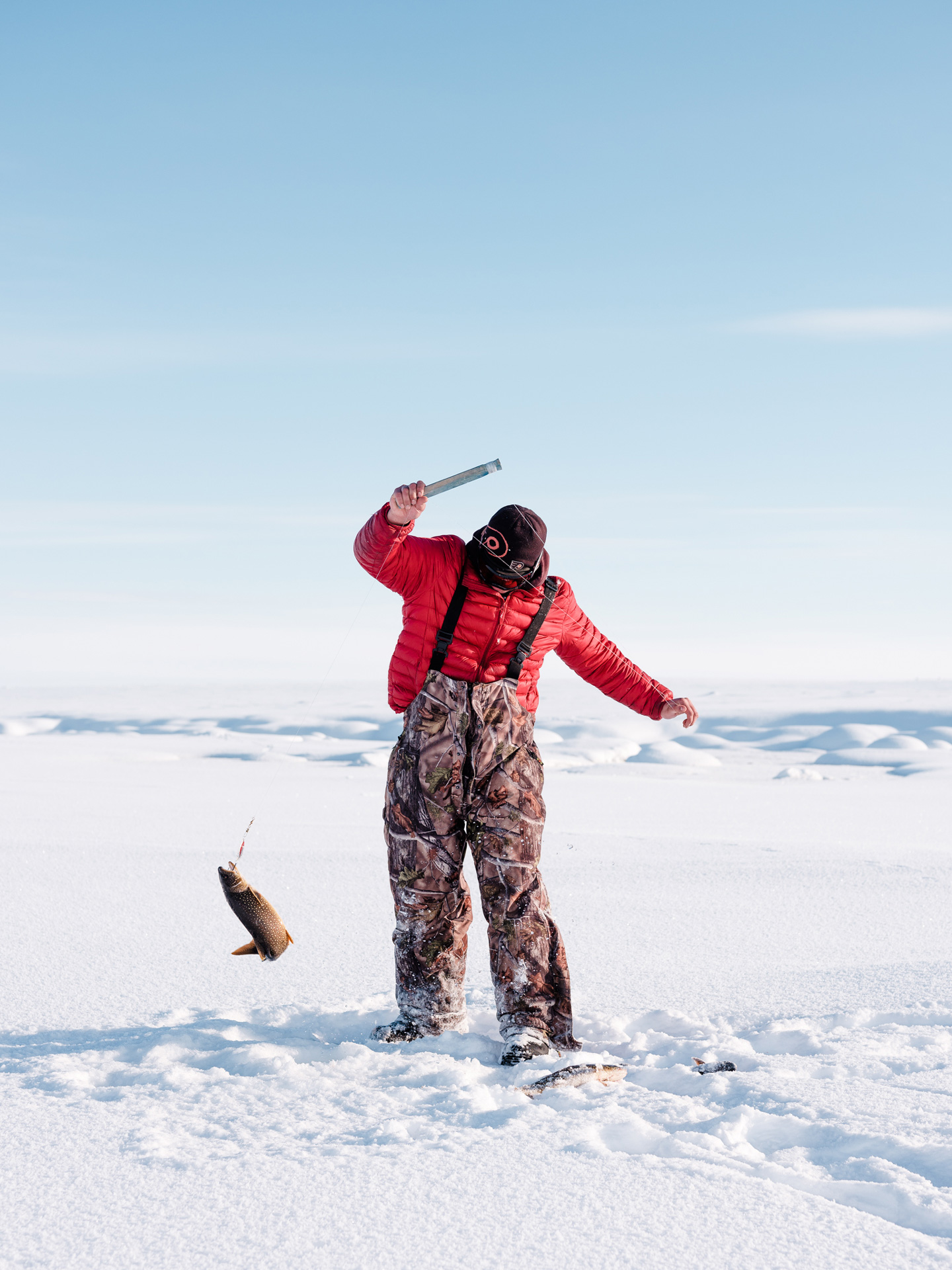 men ice-fishing on lake catching fish in Nunavik by Alexi Hobbs for Air Inuit