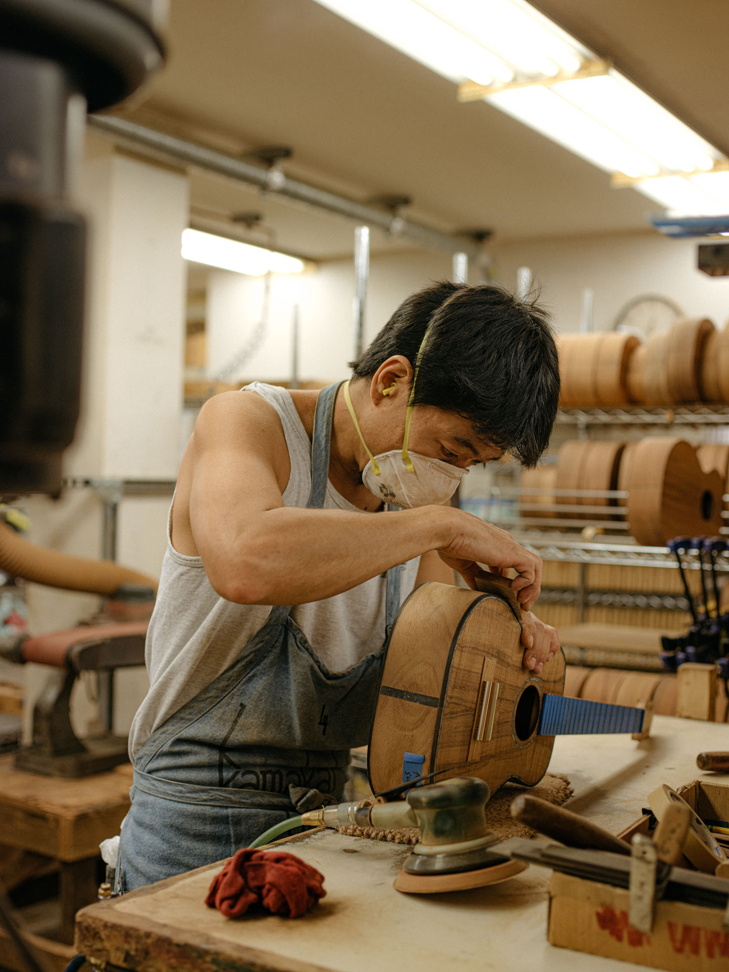 native hawaiian guitar maker working in his shop wearing mask by Alexi Hobbs in Hawai'i for enRoute Magazine