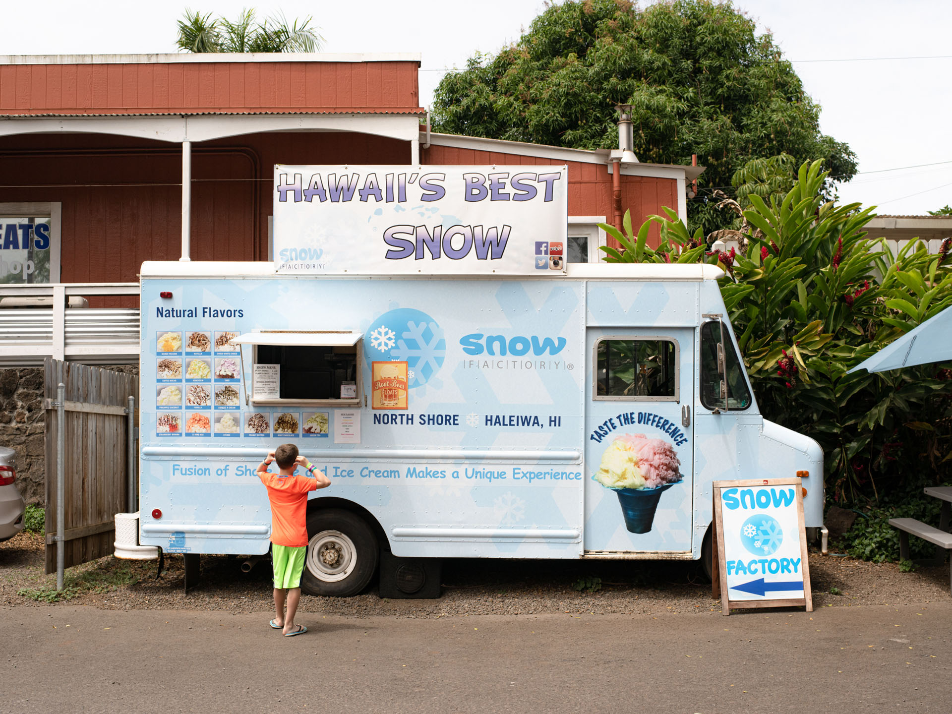 little boy in orange shirt standing in front of food truck selling shave ice snow ice by Alexi Hobbs in Hawai'i for enRoute Magazine