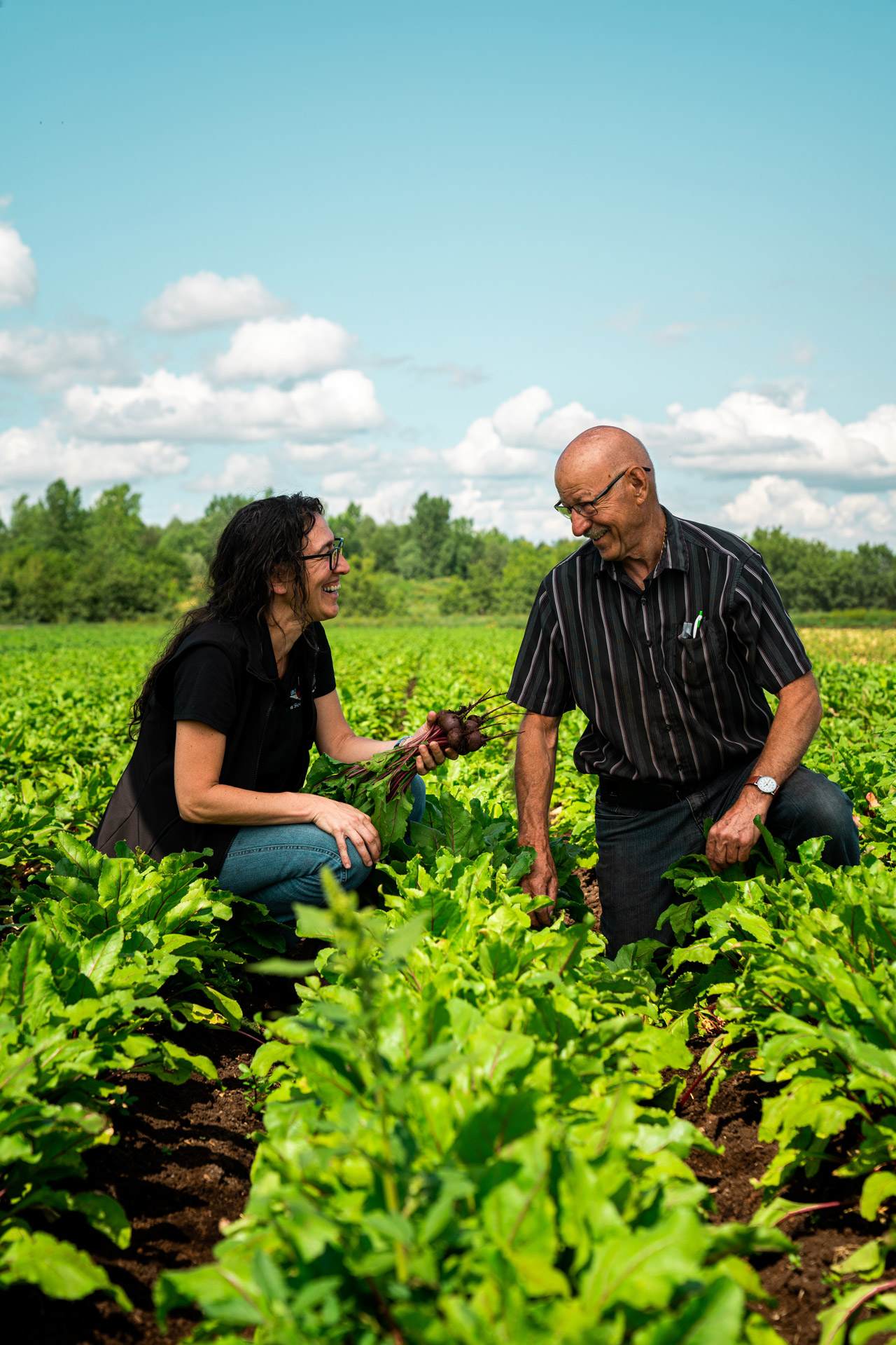 a woman and a man in a field of beets crouching on the ground laughing together by Bruno Florin for Sollio Agriculture