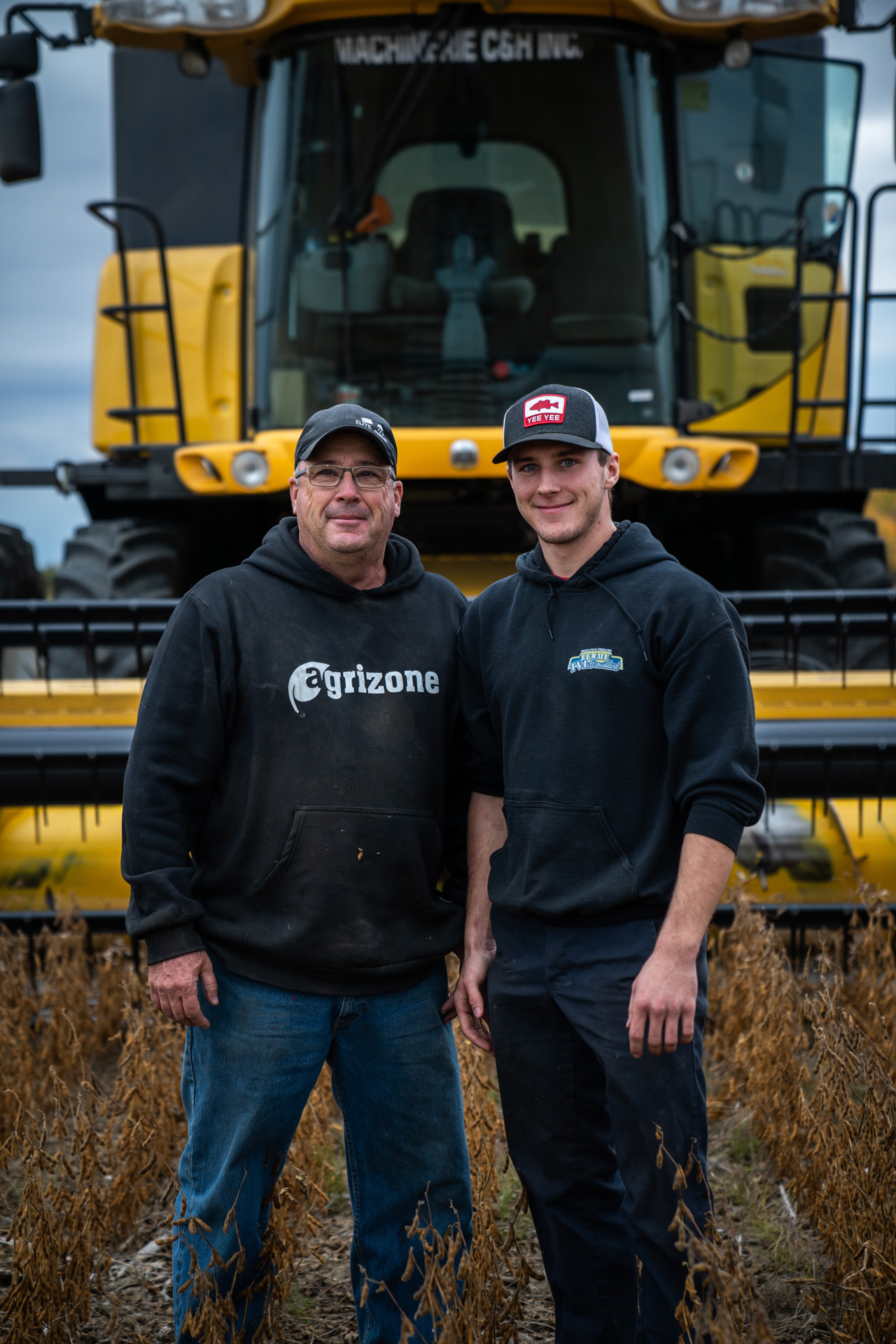 father and son in the field in front of heavy machinery smiling by Bruno Florin for Sollio Agriculture