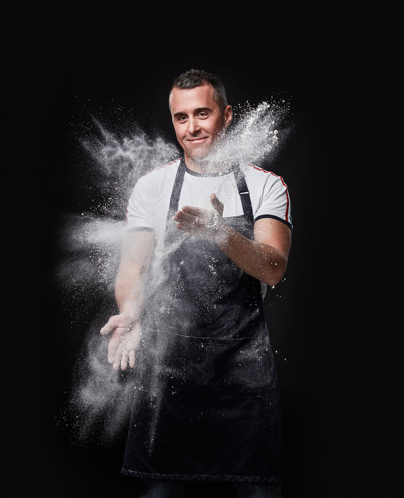 portrait of chef Federico Bianchi clapping his hands full of flour with flour flying everywhere by Jocelyn Michel for the Cathcart