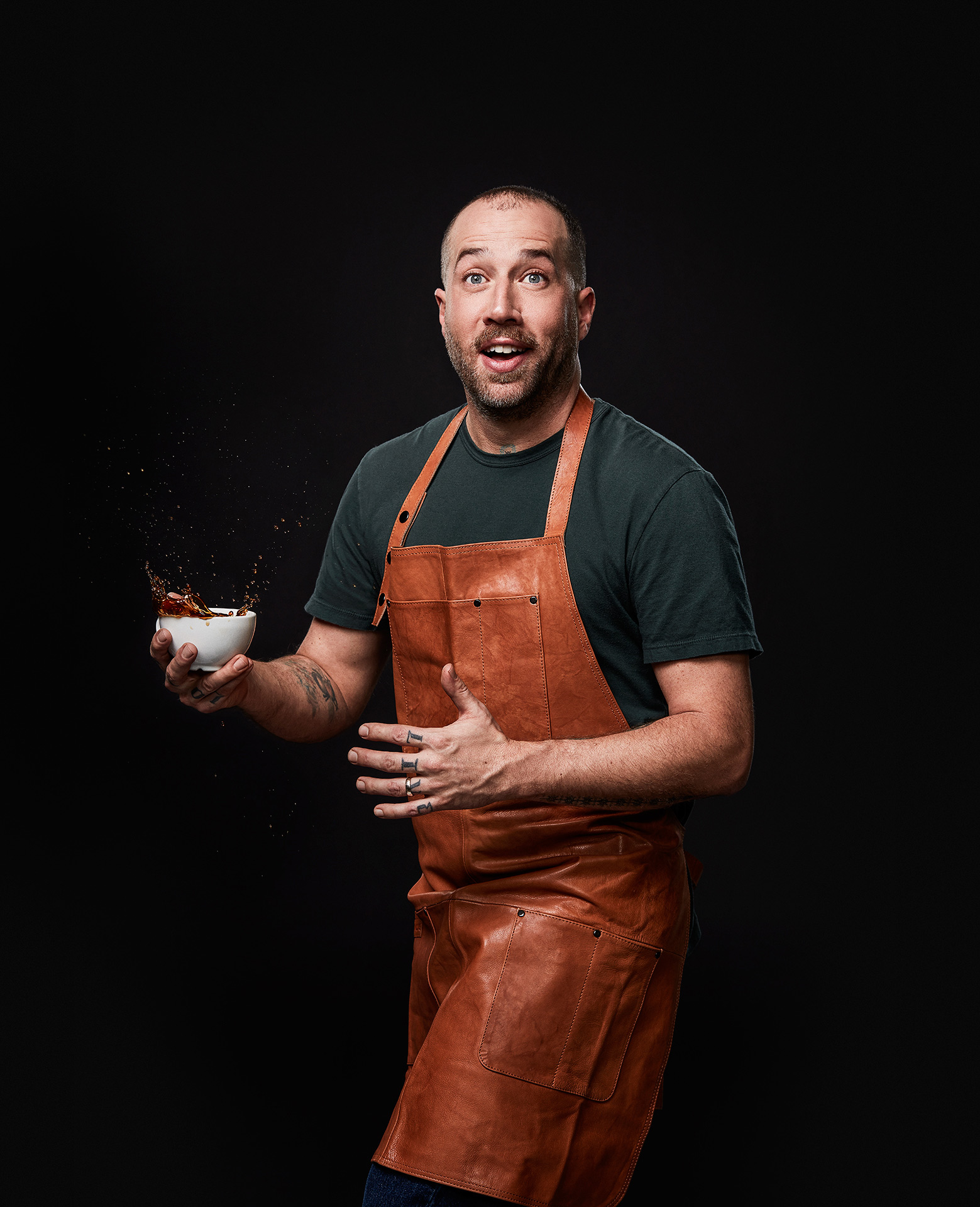 portrait of food stylist and chief Blake Mackay holding a splashing cup of coffee and acting surprised by Jocelyn Michel for the Cathcart
