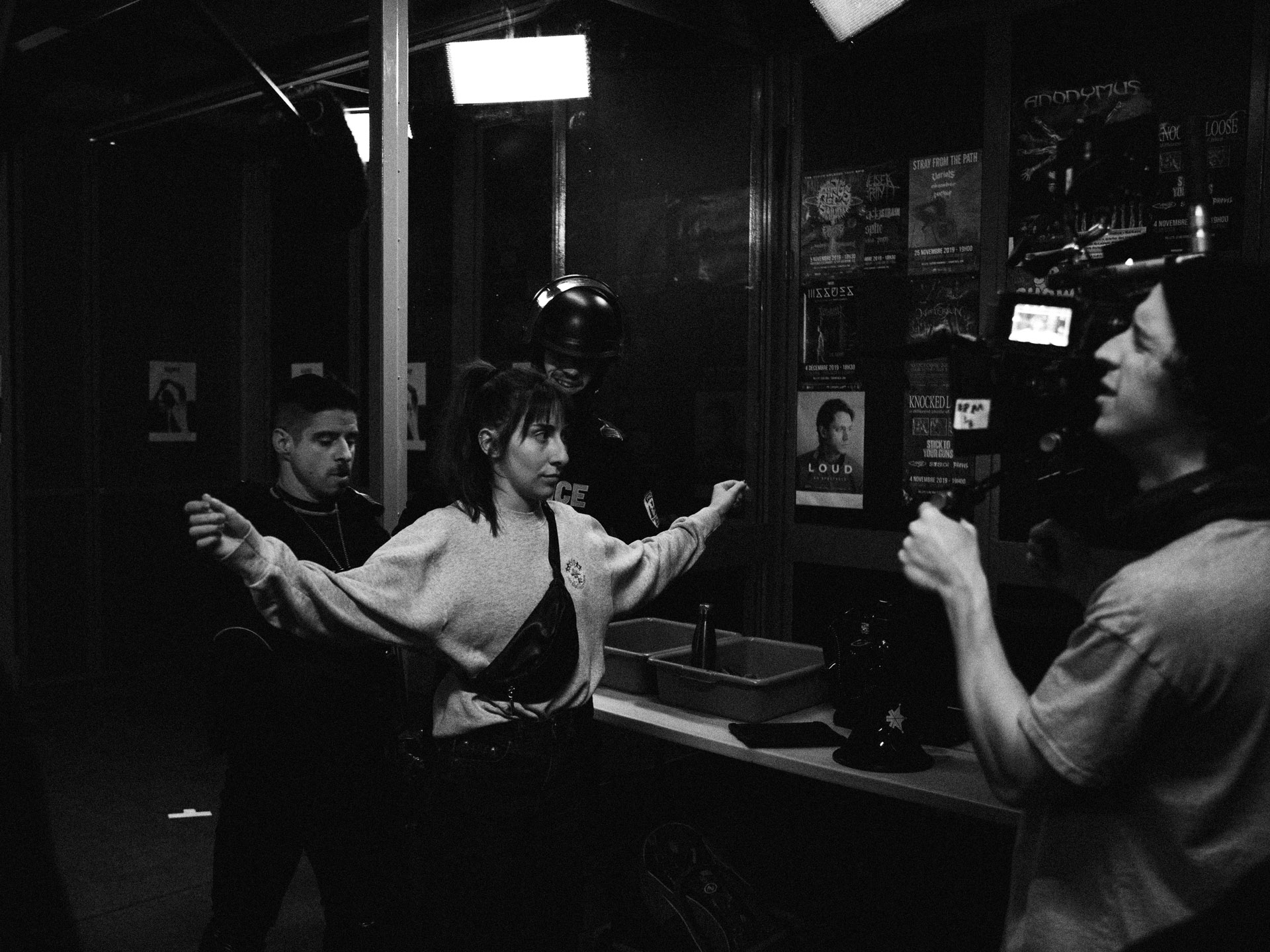 actors Hugolin Chevrette-Landesque and Emile Schneider dressed as cops checking pockets of woman in behind the scenes for TV series La Loi C'est La Loi filmed by Les Gamins for TV5 Unis