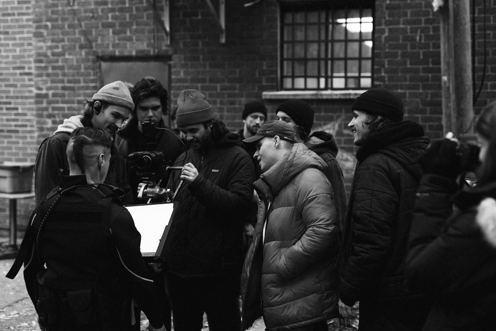 actor Hugolin Chevrette-Landesque dressed as cop with camera harnessed on him and team checking footage on camera and smiling in behind the scenes of TV series La Loi C'est La Loi filmed by Les Gamins for TV5 Unis