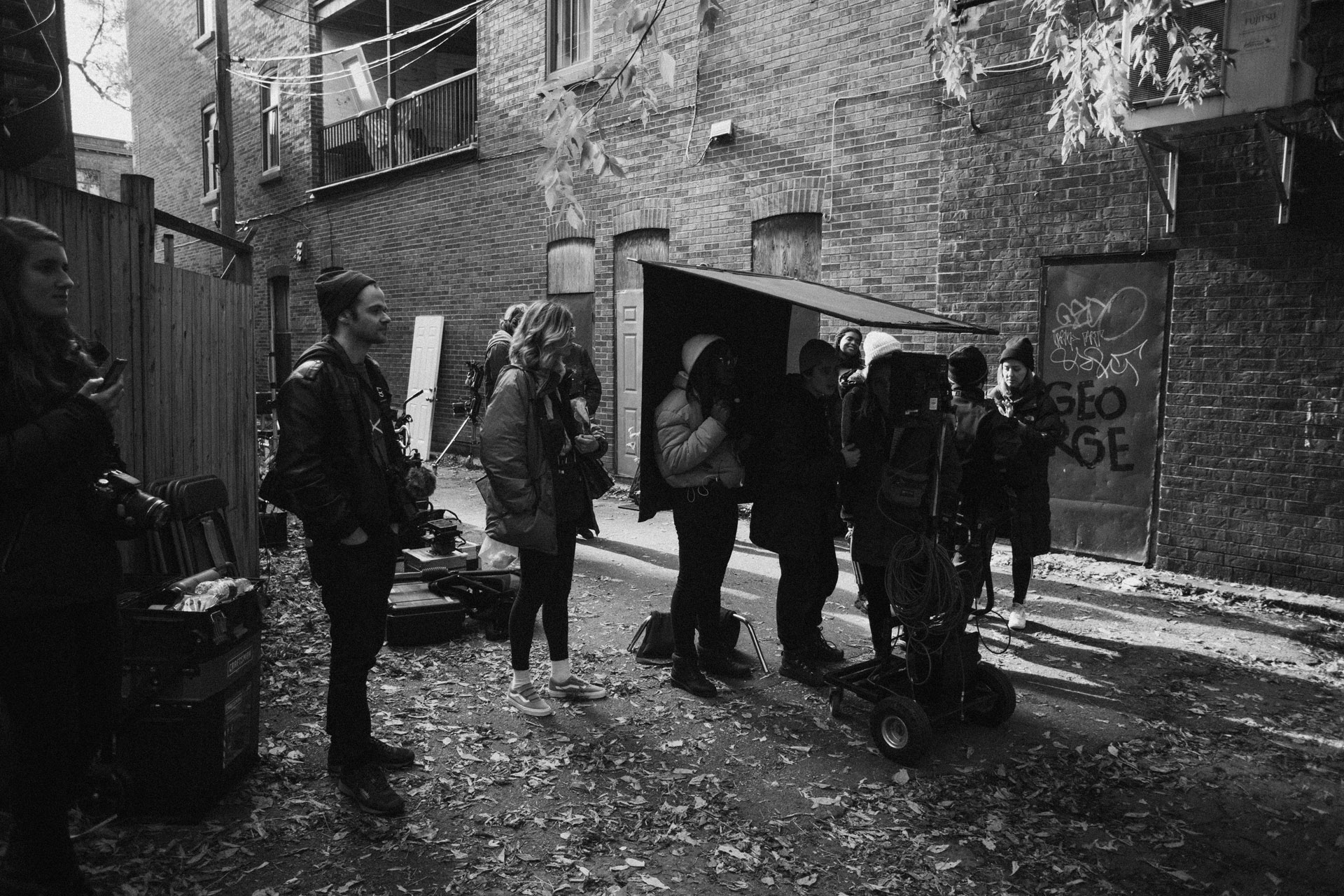 Vincent Ruel-Cote from Les Gamins filming with huge camera protected under panels huddled with team members in behind the scenes filming TV series La Loi C'est La Loi at night with TV5 Unis