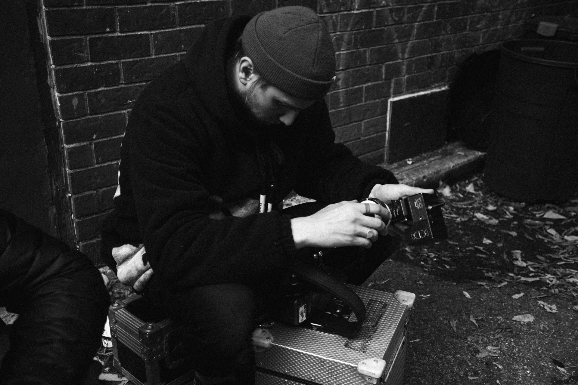 man sitting on the ground in alley directing the camera's focus in behind the scenes for TV series La Loi C'est La Loi filmed by Les Gamins for TV5 Unis