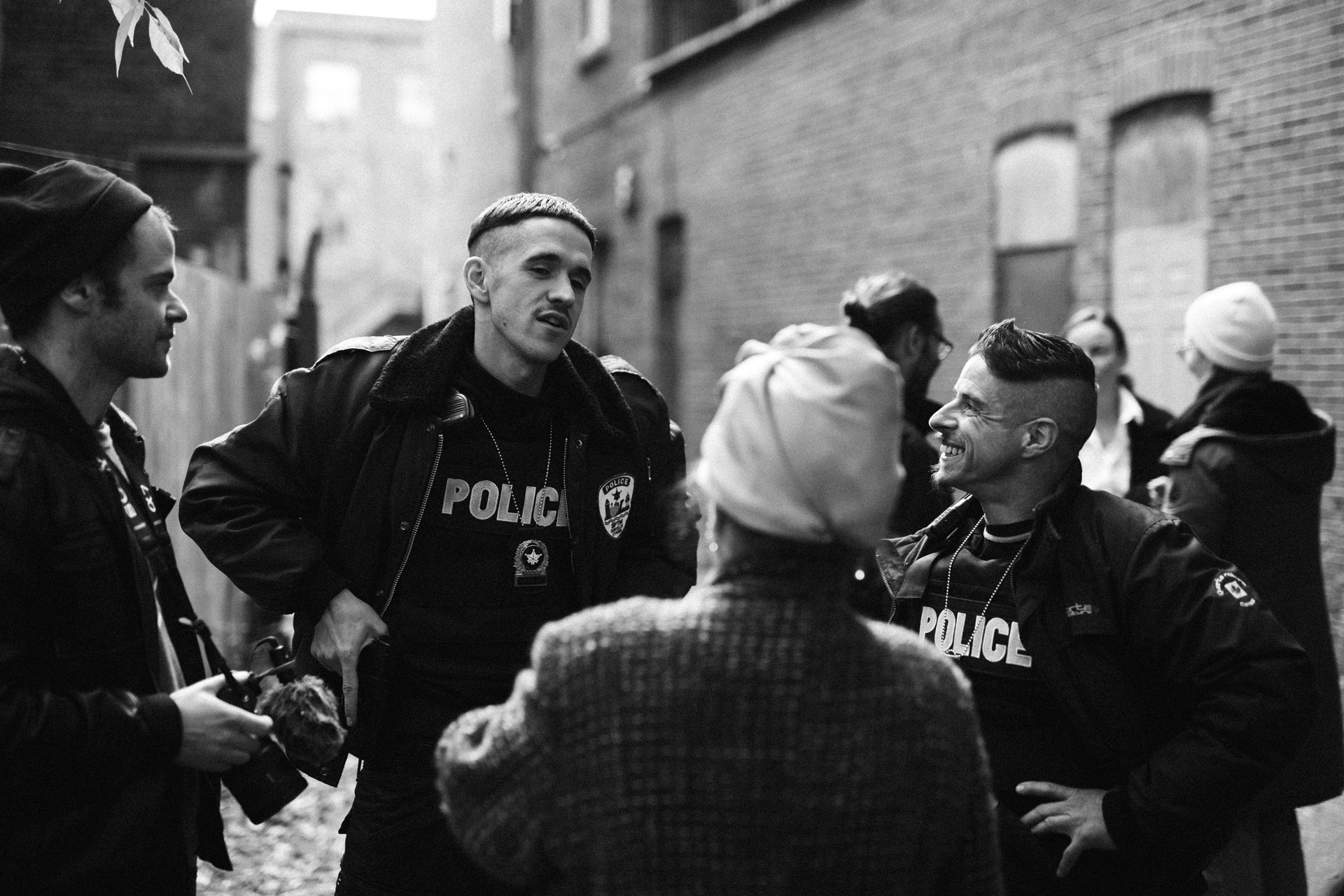 actors Hugolin Chevrette-Landesque and Emile Schneider dressed as cops talking and laughing with the filming team in behind the scenes for TV series La Loi C'est La Loi filmed by Les Gamins for TV5 Unis