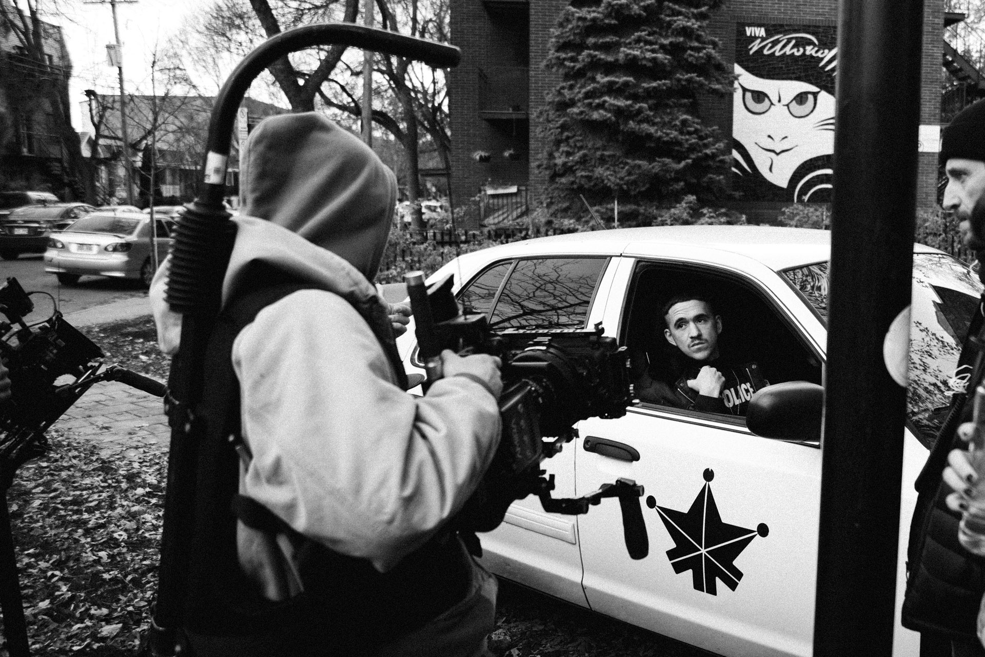 camera assistant filming actor Emile Schneider getting out of police car in behind the scenes of TV series La Loi C'est La Loi filmed by Les Gamins for TV5 Unis