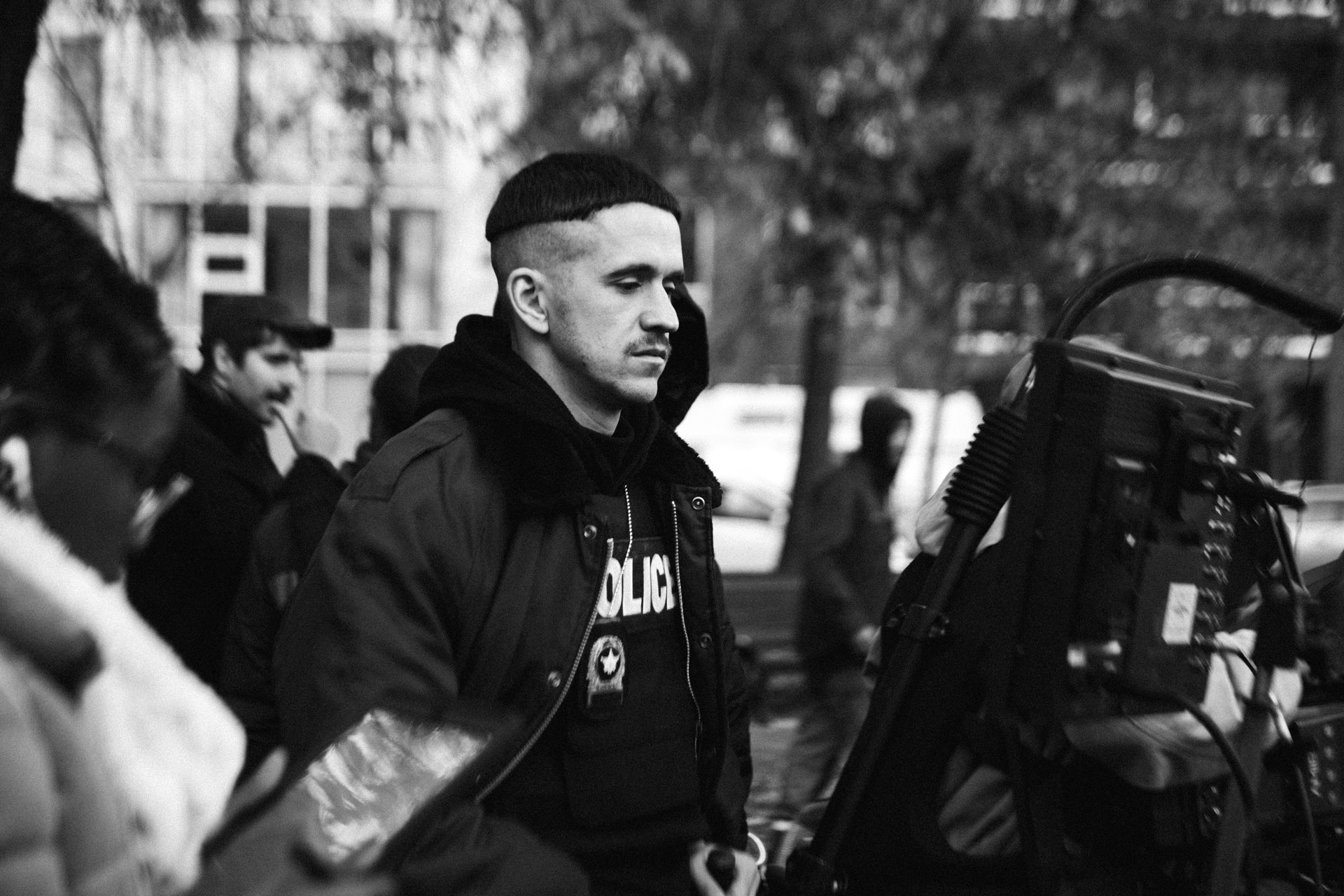 actor Emile Schneider dressed as cop checking footage on a screen looking serious in behind the scenes of TV series La Loi C'est La Loi filmed by Les Gamins for TV5 Unis