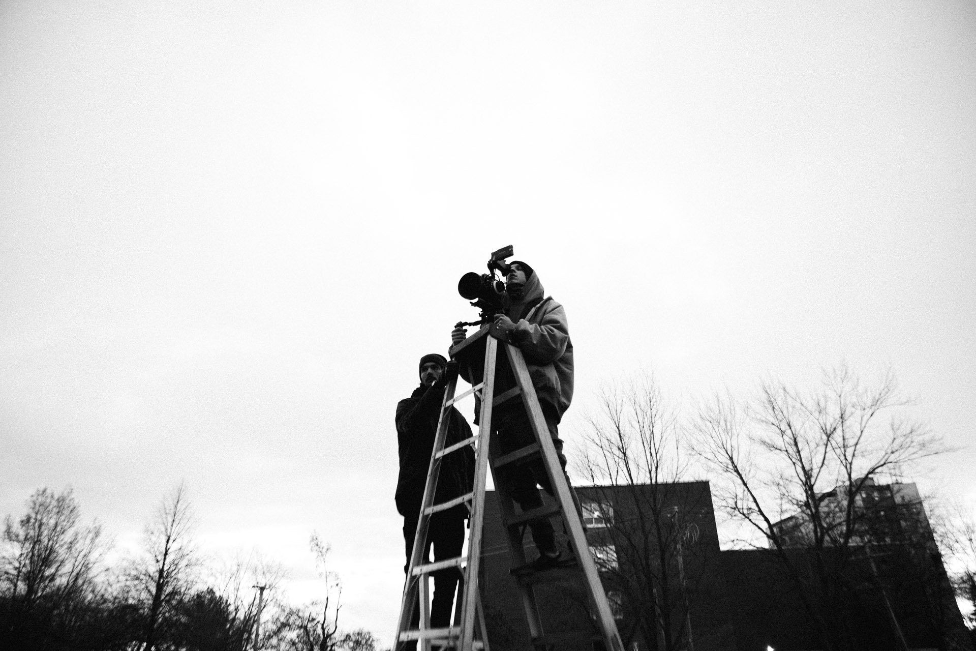Vincent Ruel-Cote from Les Gamins up on a ladder with camera assistant to film a top view in behind the scenes filming TV series La Loi C'est La Loi at night with TV5 Unis