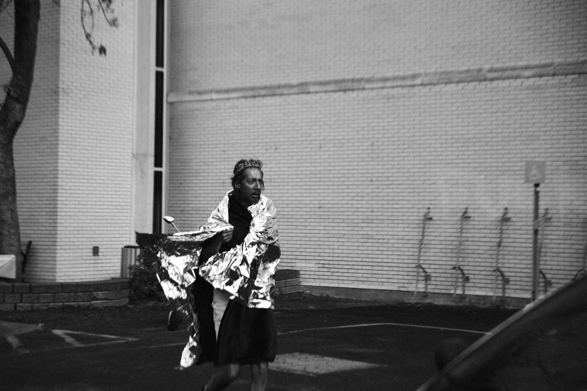 actor playing cult guru all covered in blue makeup keeping warm with safety blanket alone in parking lot looking lost in behind the scenes of TV series La Loi C'est La Loi filmed by Les Gamins for TV5 Unis