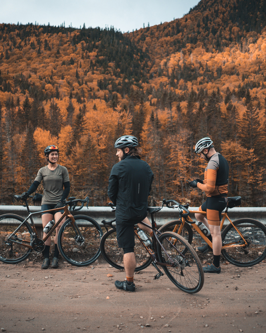 trio of long distance bikers talking on side of the road with mountains covered in orange colored trees in the background for Spring Summer 2020 campaign of Louis Garneau with artistic direction and styling by Studio TB